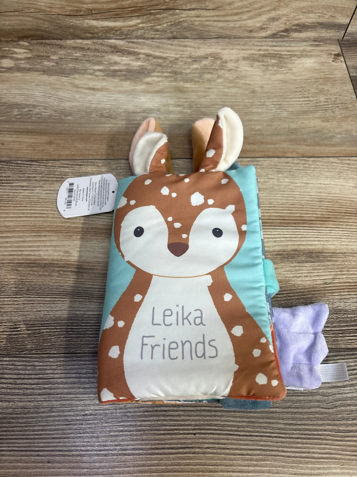 Front view of new Mary Meyer Leika Friends soft cloth book showcasing plush deer cover with hangtag attached on wood plank floor