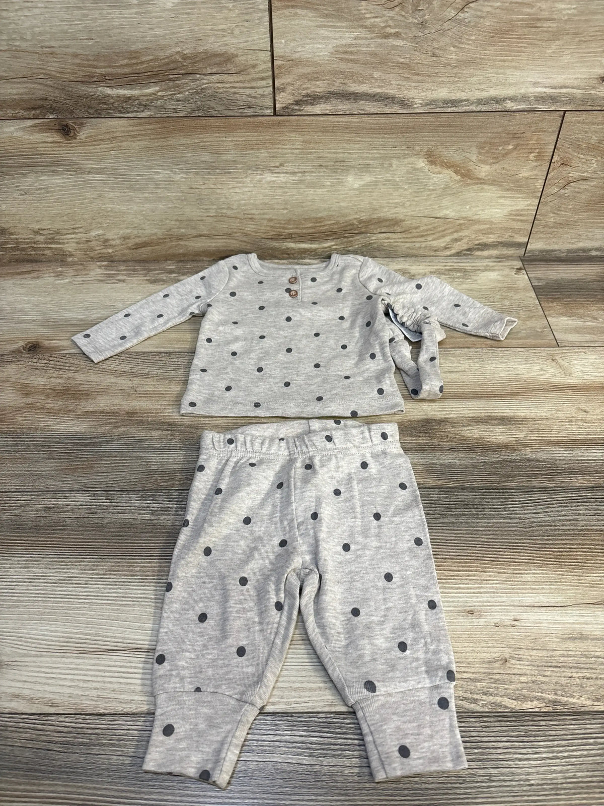 Flat lay of Just One You 3-piece tan baby set showing long-sleeve polka-dot shirt, elastic-waist pants, and matching headband on wooden floor