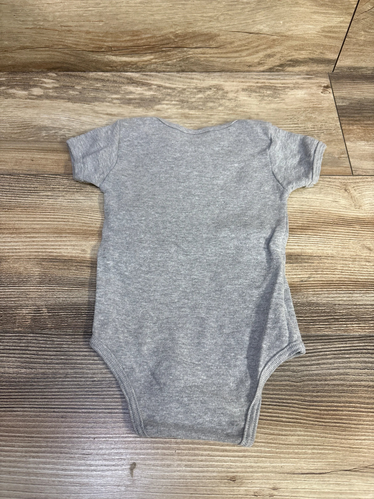 Back view of American Apparel grey baby bodysuit size 3-6m showing short sleeves laid flat on wood background