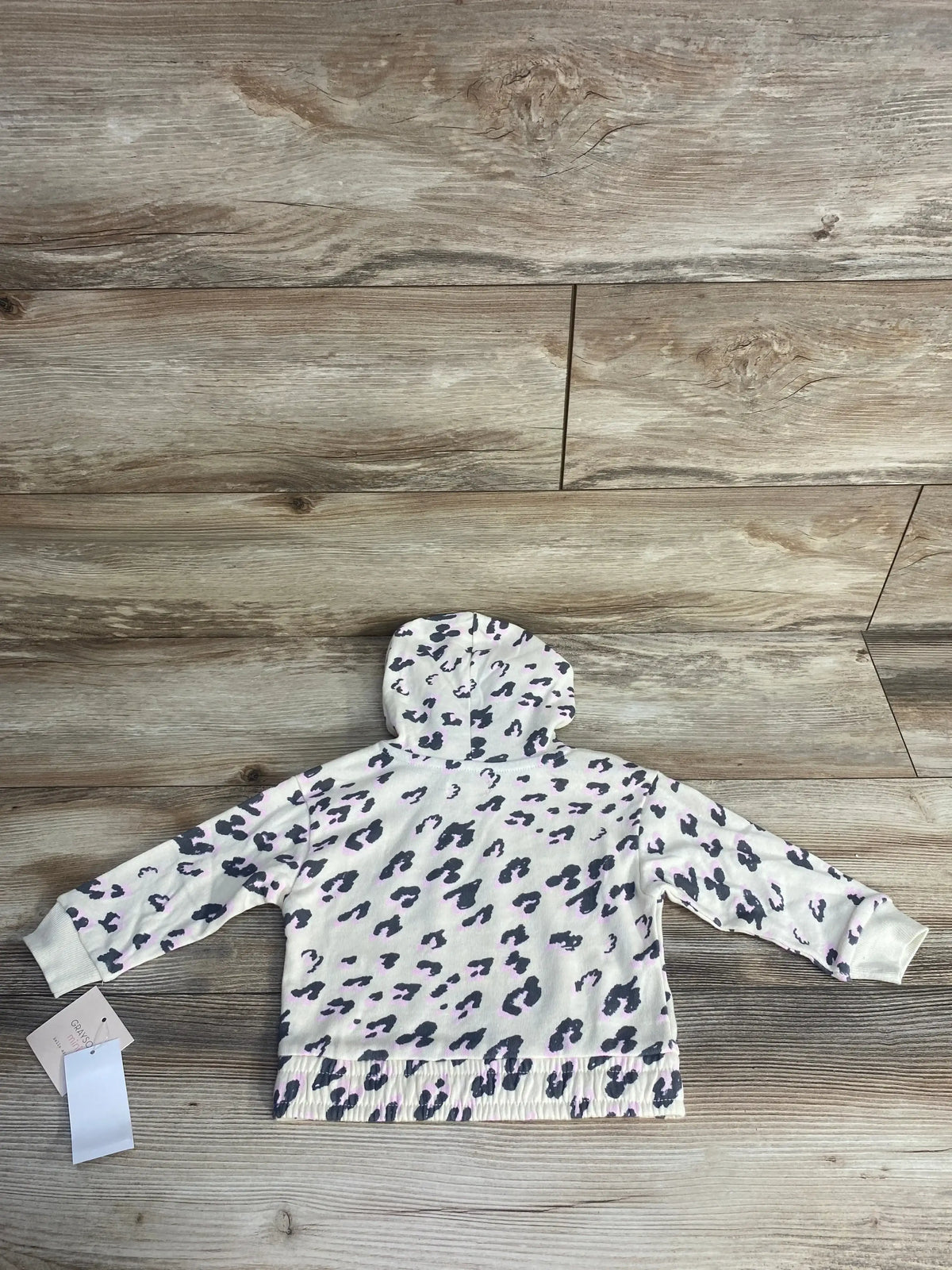 White toddler hoodie with gray and pink leopard print laid flat on wood floor
