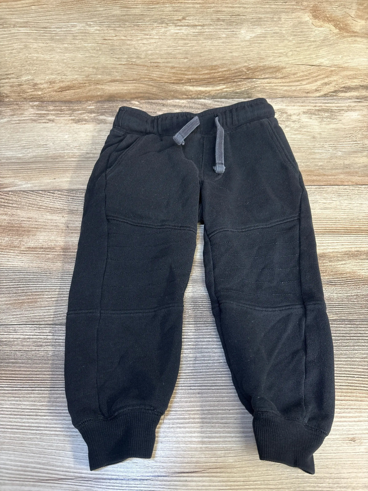 Black kids jogger sweatpants with drawstring waistband on wood background