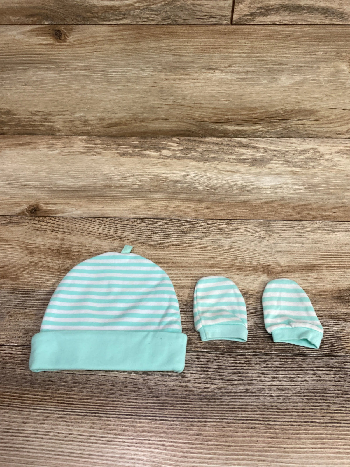 Aqua and white striped baby cap and mittens set for sizes 0-3m on a wooden surface