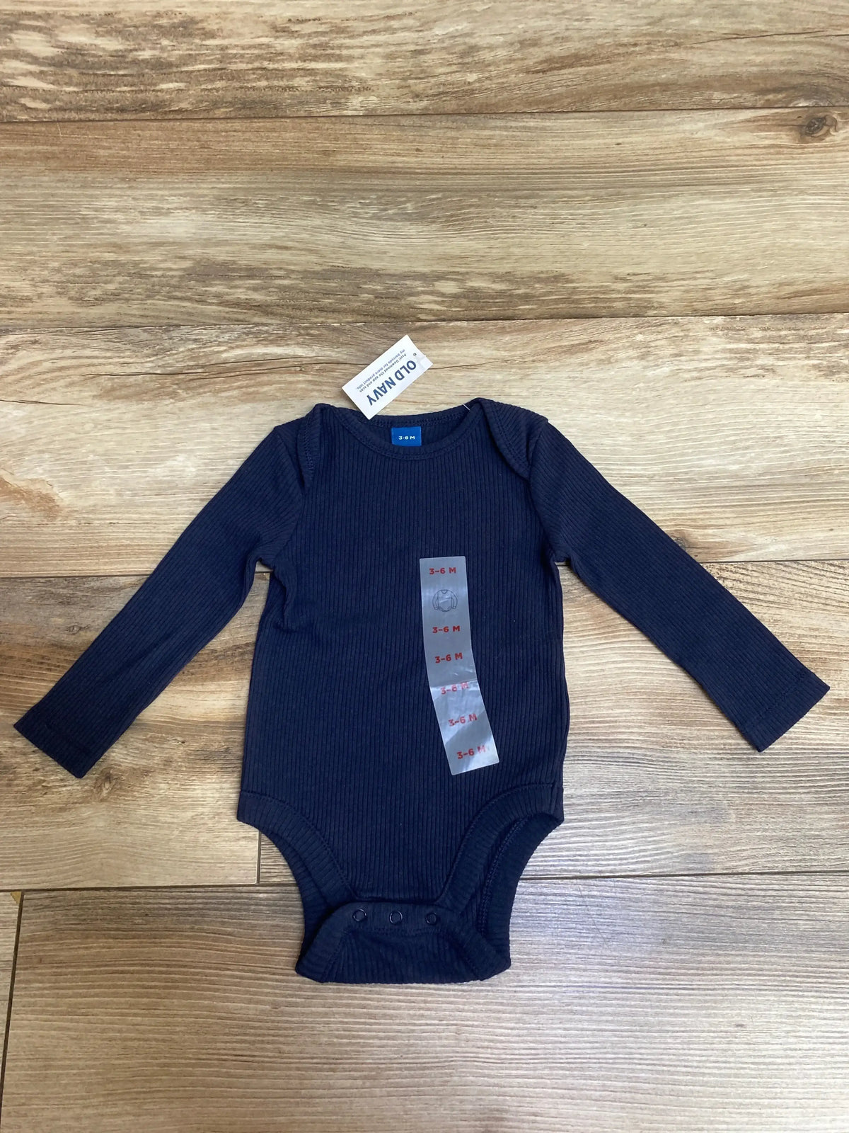 Navy blue ribbed long-sleeve baby bodysuit sized 3-6 months from Old Navy on wooden floor