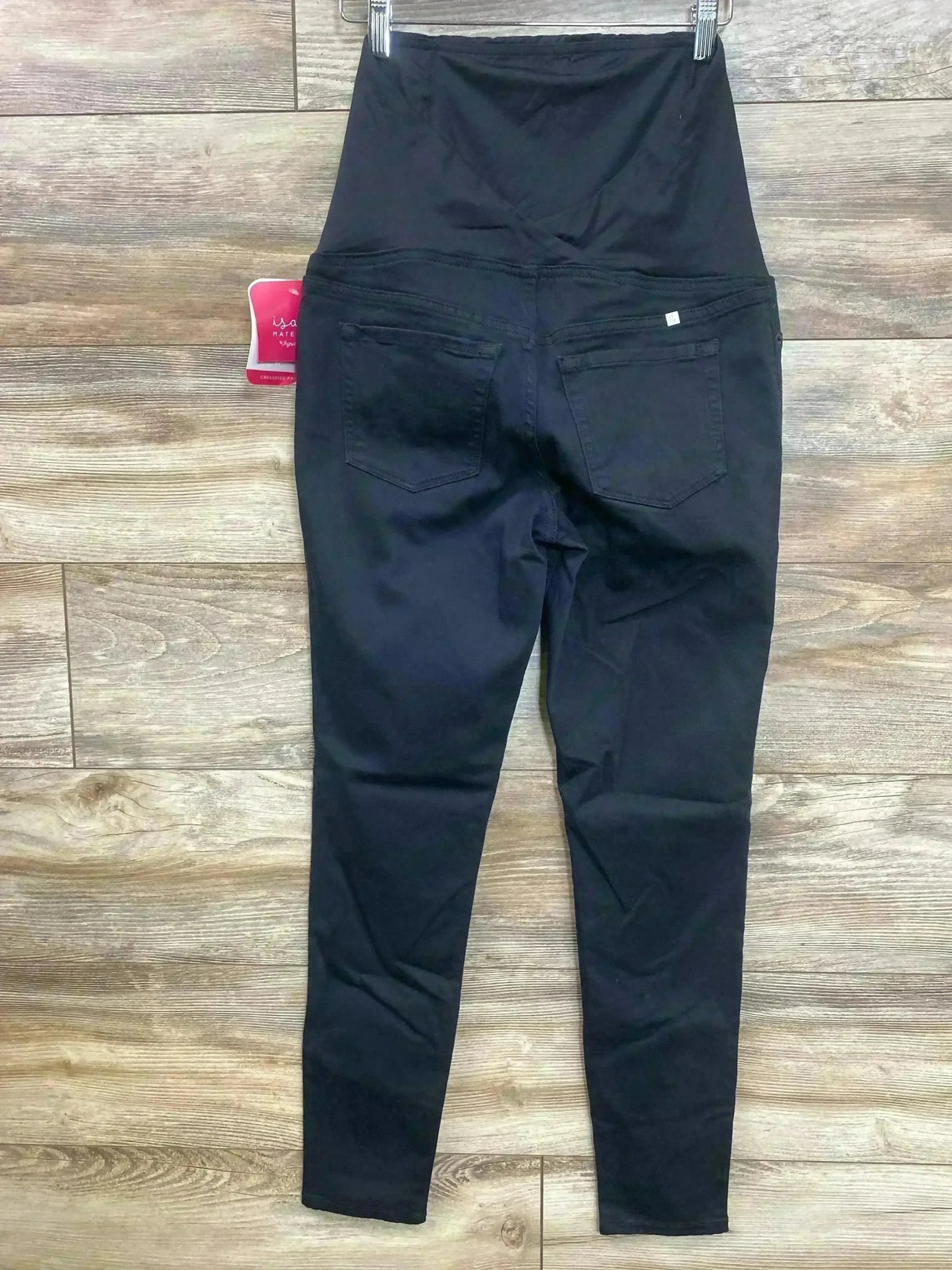 Back view of Isabel maternity skinny jeans in black showing crossover belly panel and back pockets on wood floor