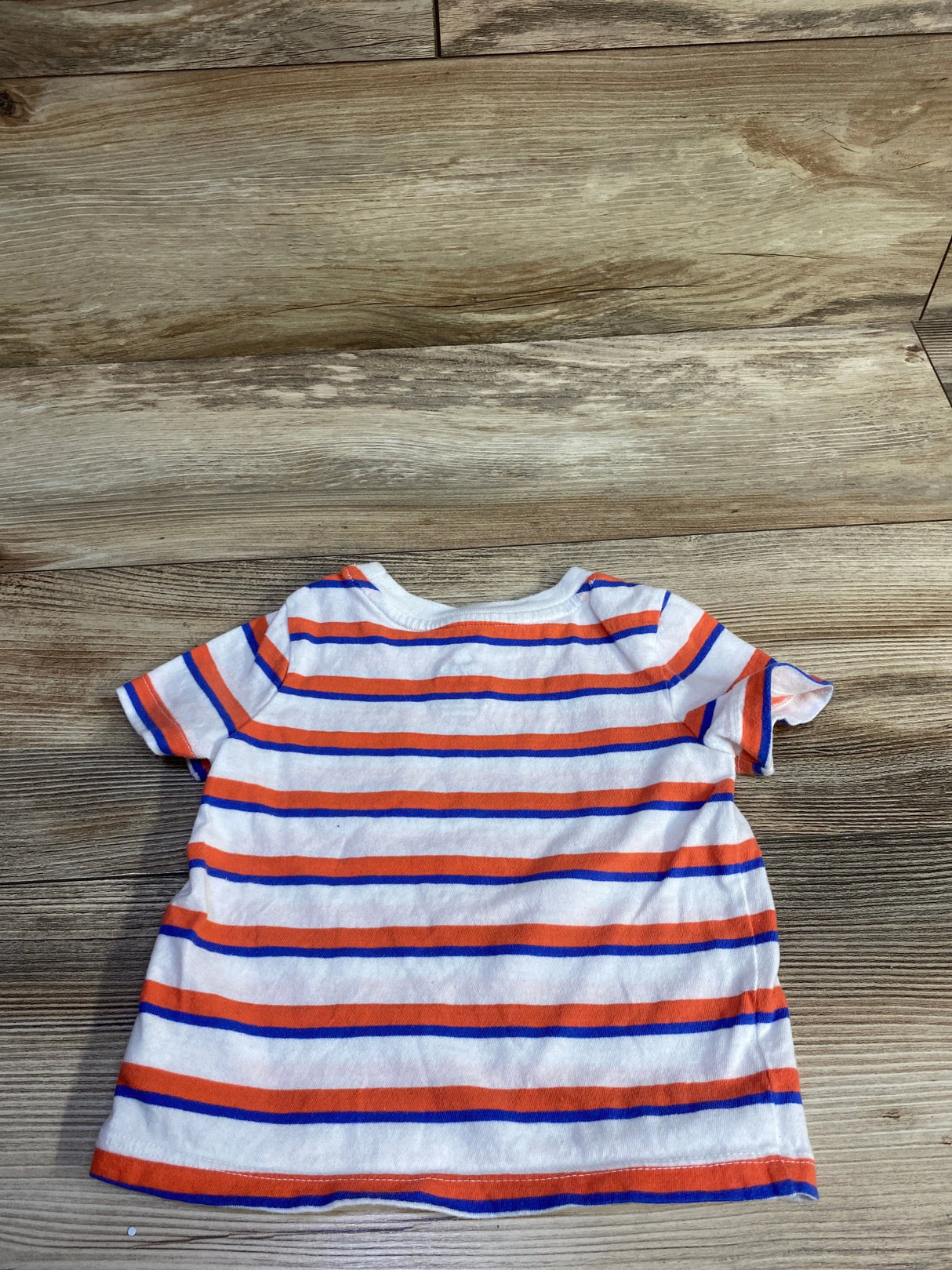 Flat lay back view of Baby Gap short-sleeve striped shirt showing orange and blue horizontal stripes on white on wood floor background