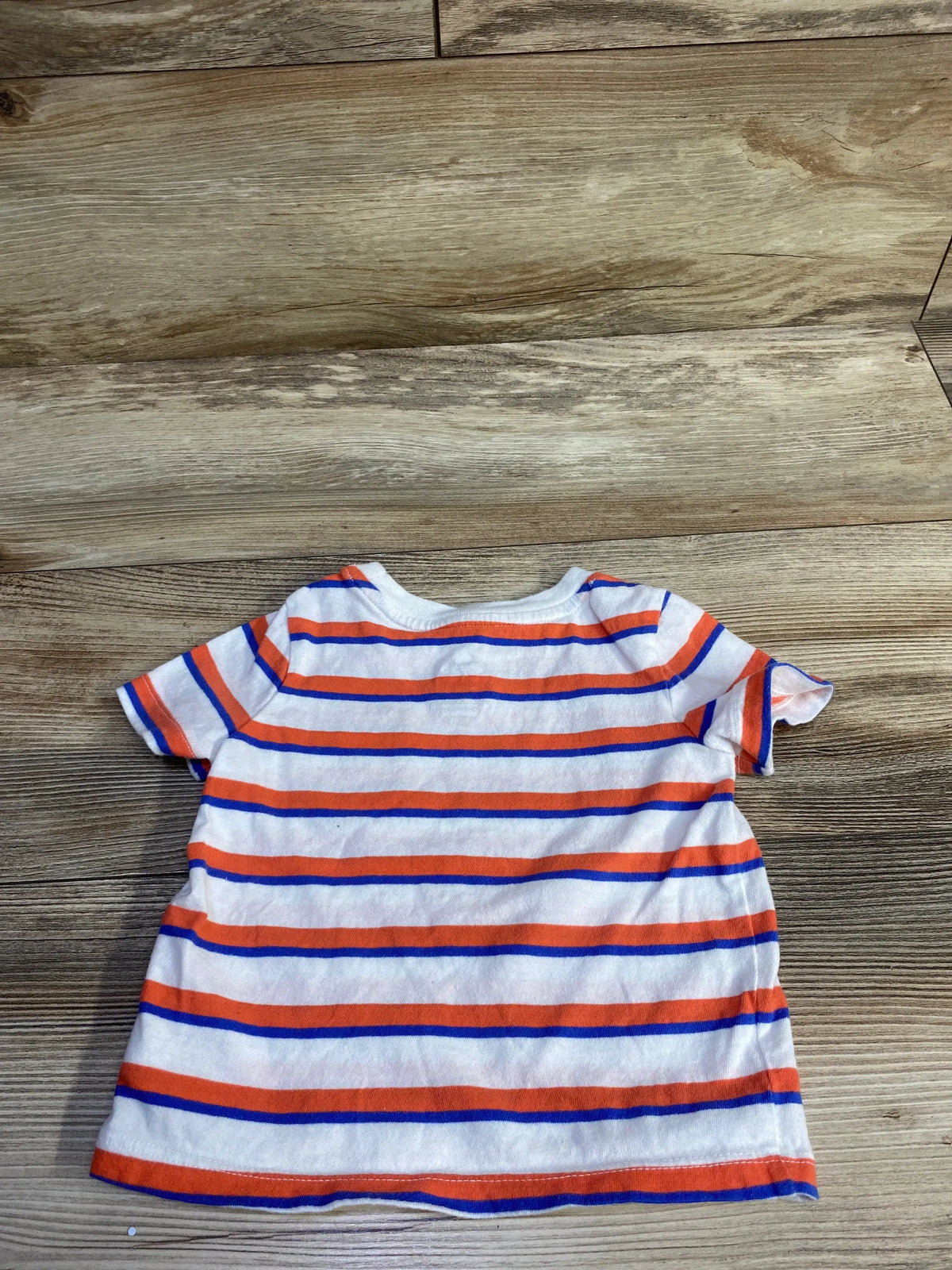 Flat lay back view of Baby Gap short-sleeve striped shirt showing orange and blue horizontal stripes on white on wood floor background