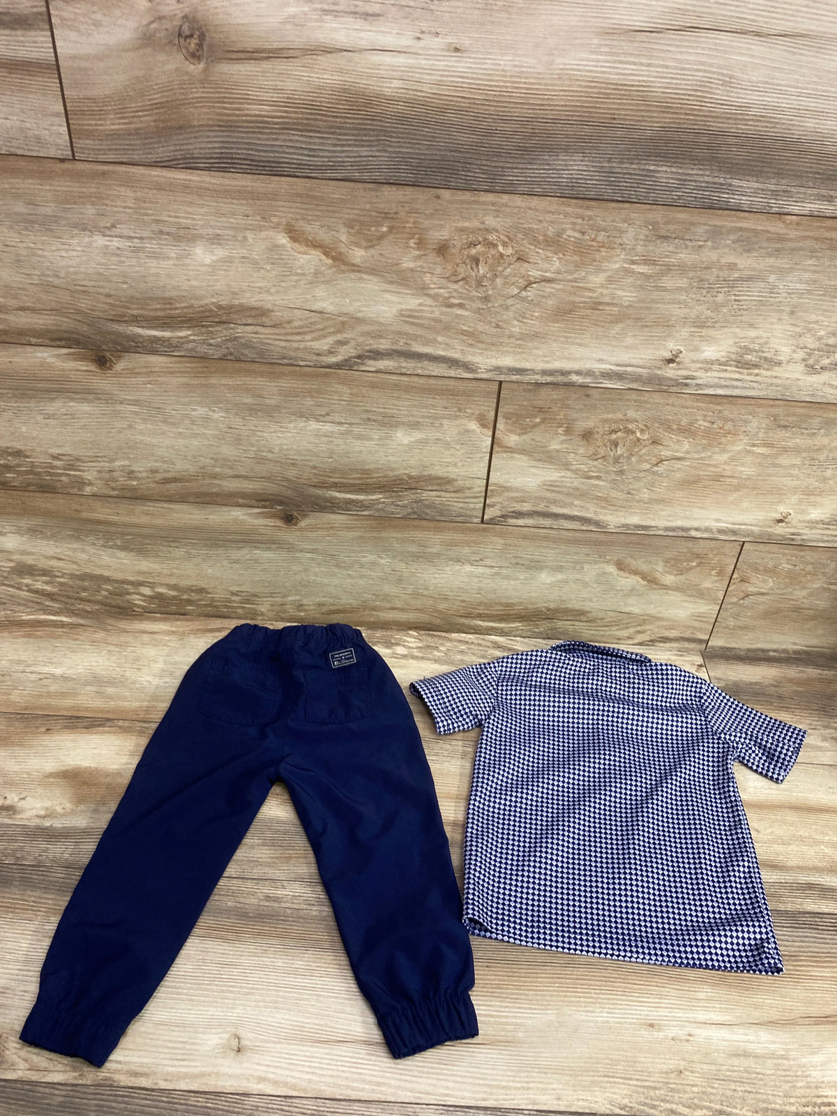 Top view of Ben Sherman tech polo and pant set in size 24 months, with patterned polo and elastic cuff pants on wood flooring