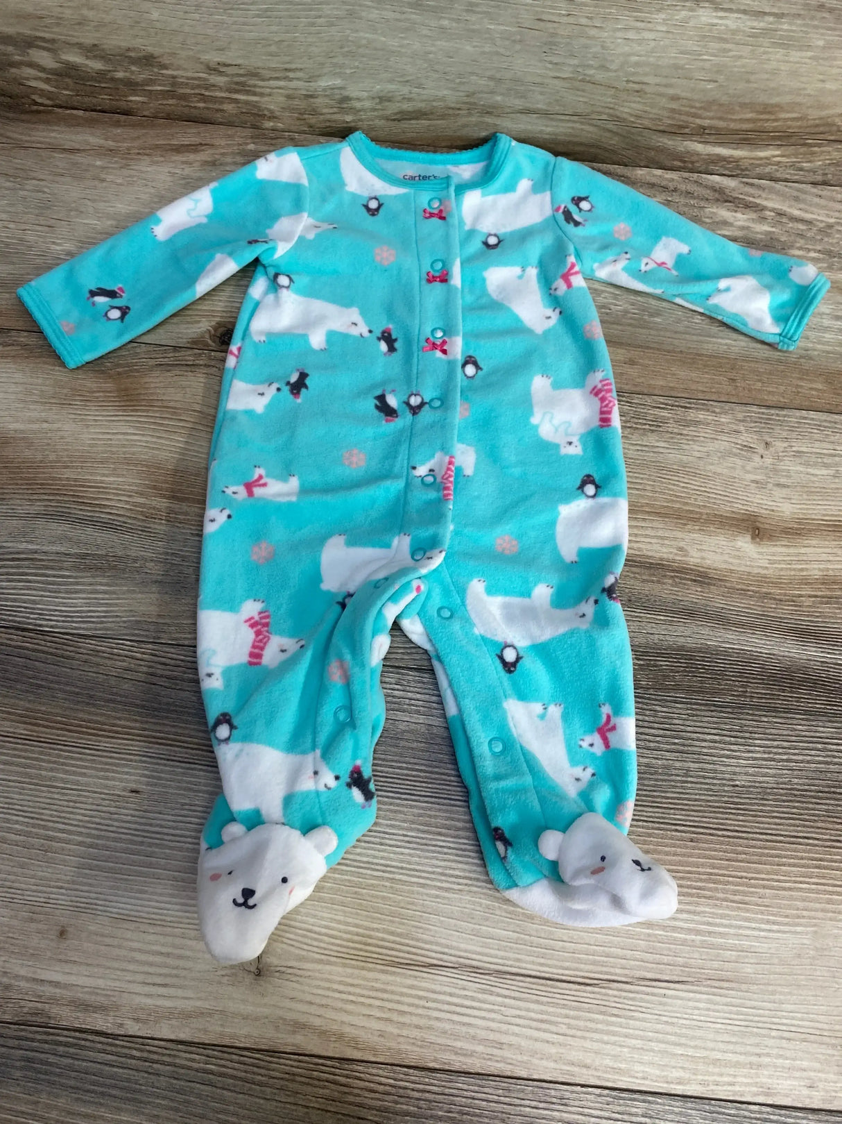 Front view of Carter’s blue footed sleeper size 3M with polar bear and penguin print, snap front closure, and bear-face footies on wood floor