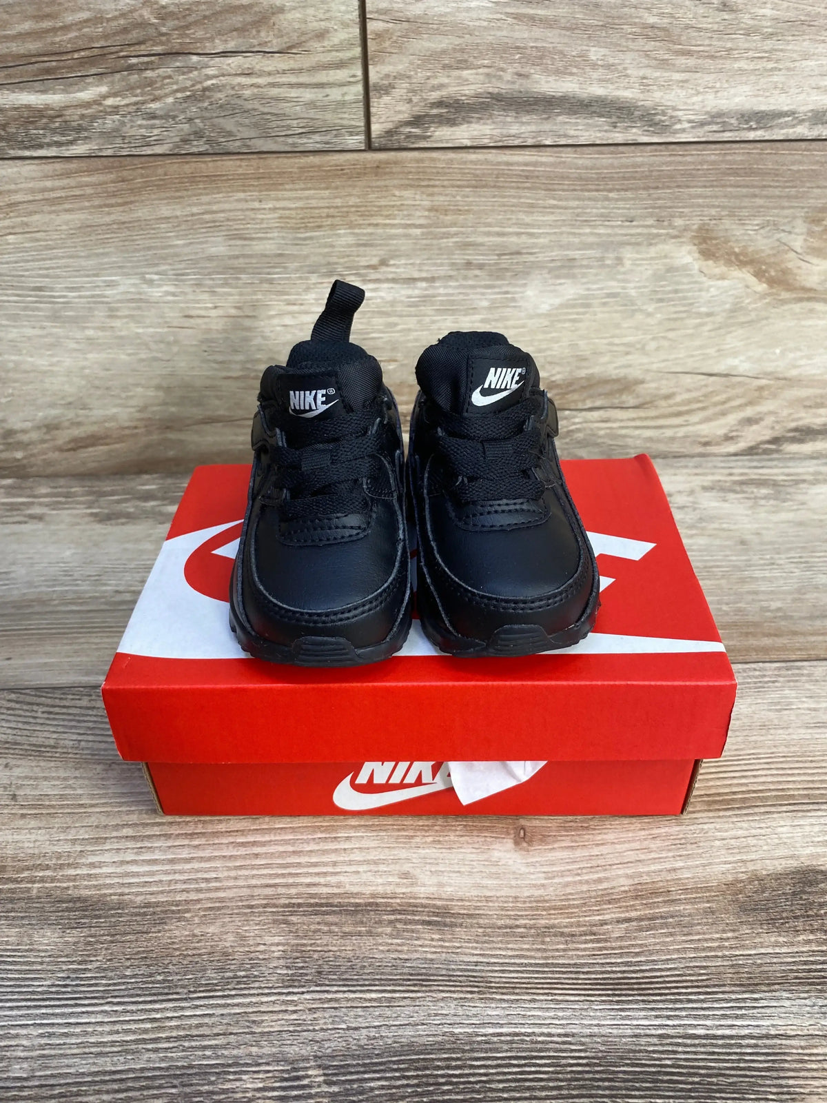 Front view of toddler Nike Air Max 90 EasyOn sneakers, size 4C, triple black with pull tab and Nike logos on red Nike box
