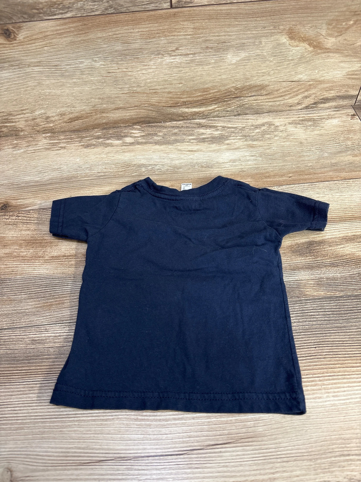 Back view of navy Baby Shark birthday short-sleeve toddler T-shirt, size 12 months, laid flat on wood floor