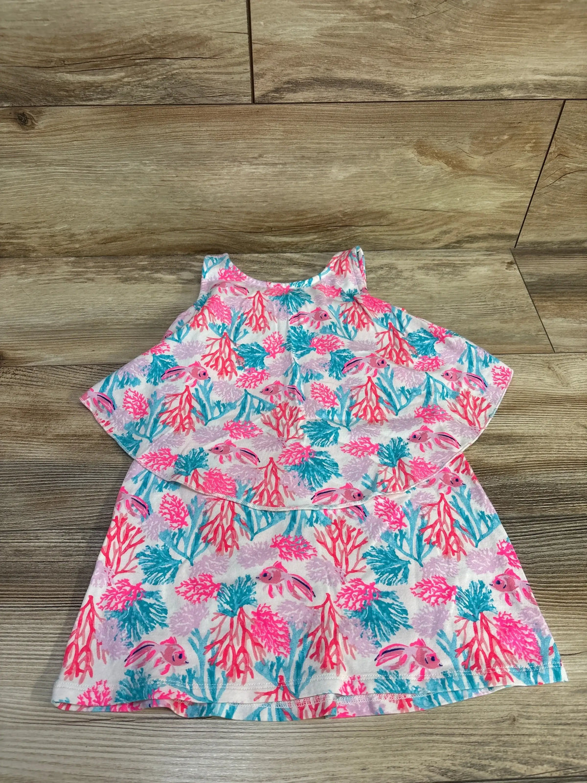 Front view of EGG coral print sun dress in pink, size 2T, showcasing sleeveless styling with a coral and fish print on a wood floor