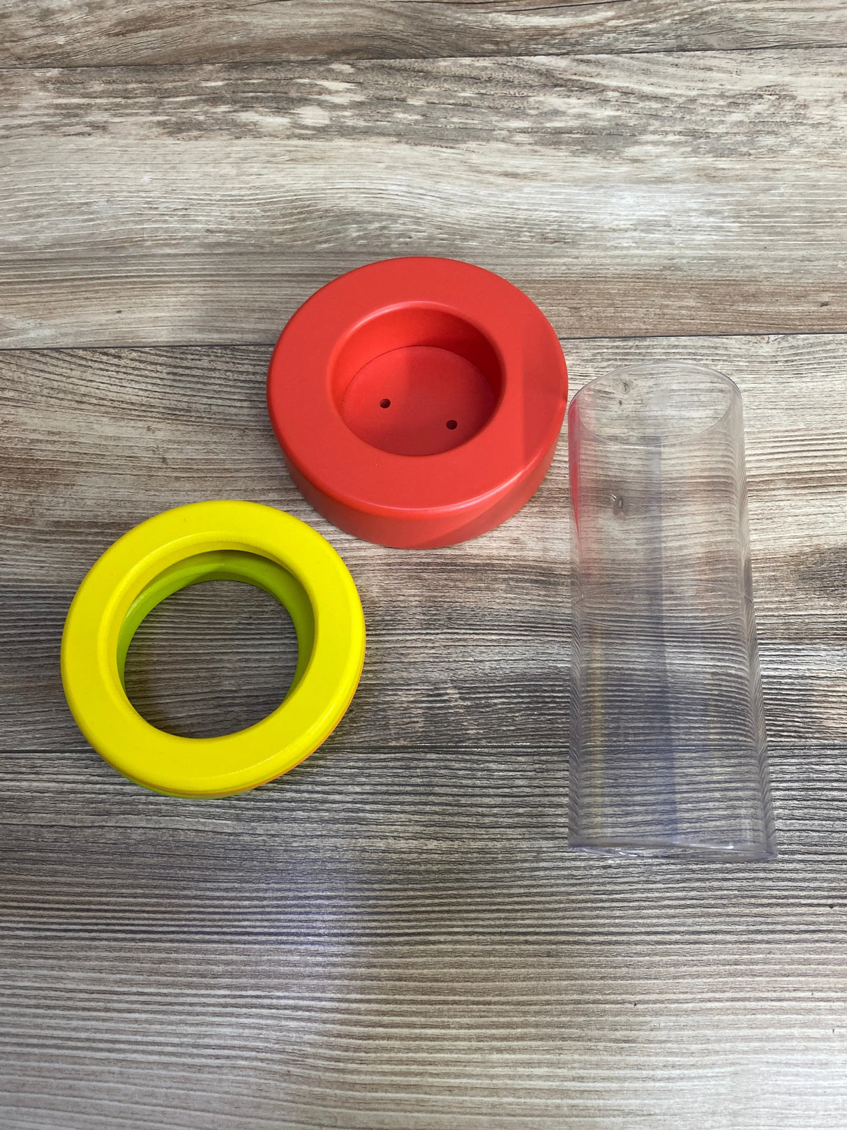 Colorful plastic toy rings and clear tube on wood background, kids stacking toy parts