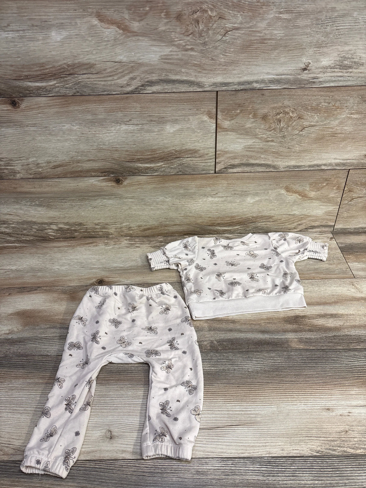 Infant two-piece outfit with butterfly print, including long sleeve top and pants on wooden floor