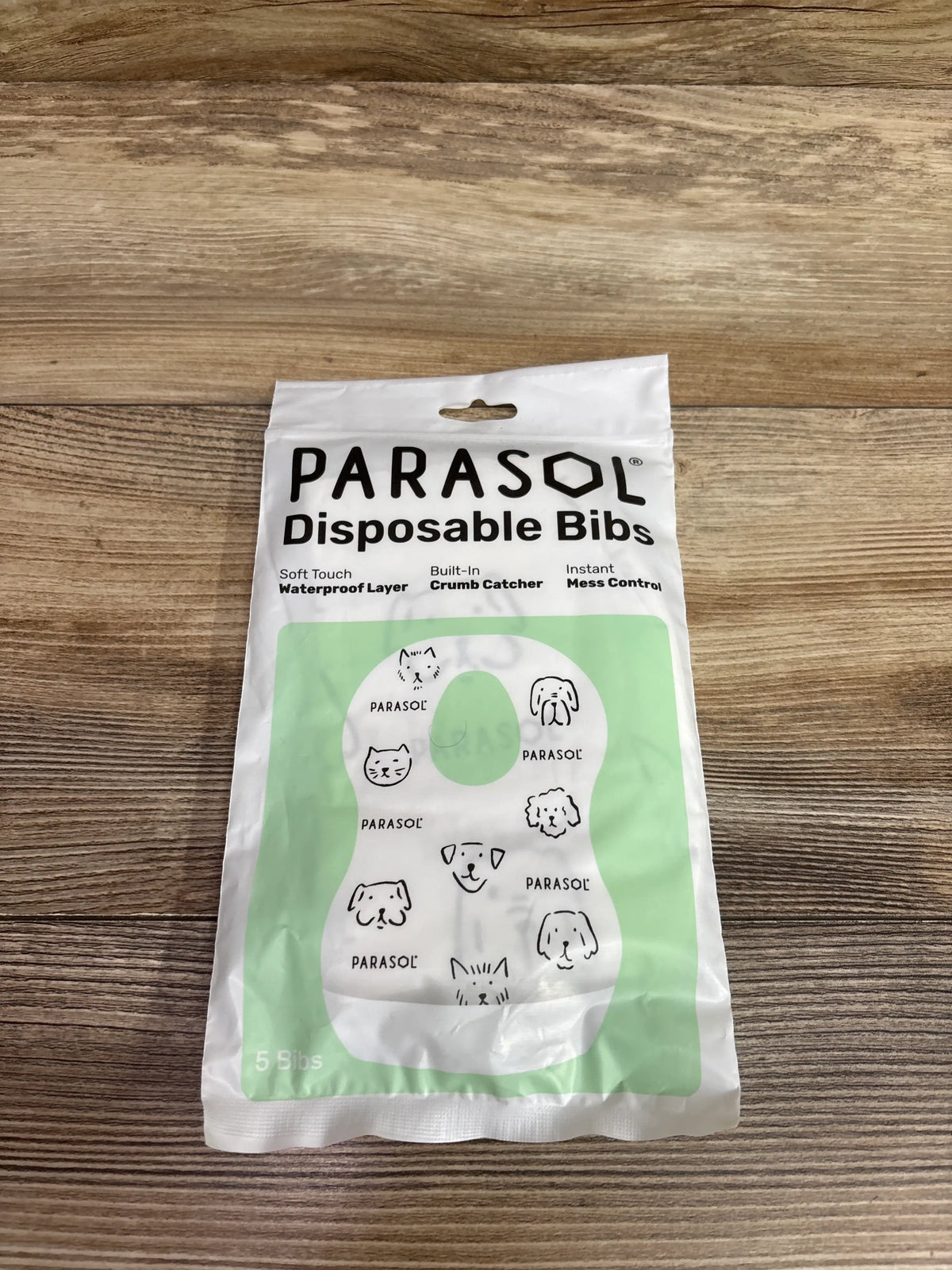 Front view of Parasol disposable bibs 5pk package showcasing waterproof layer, built-in crumb catcher, and instant mess control