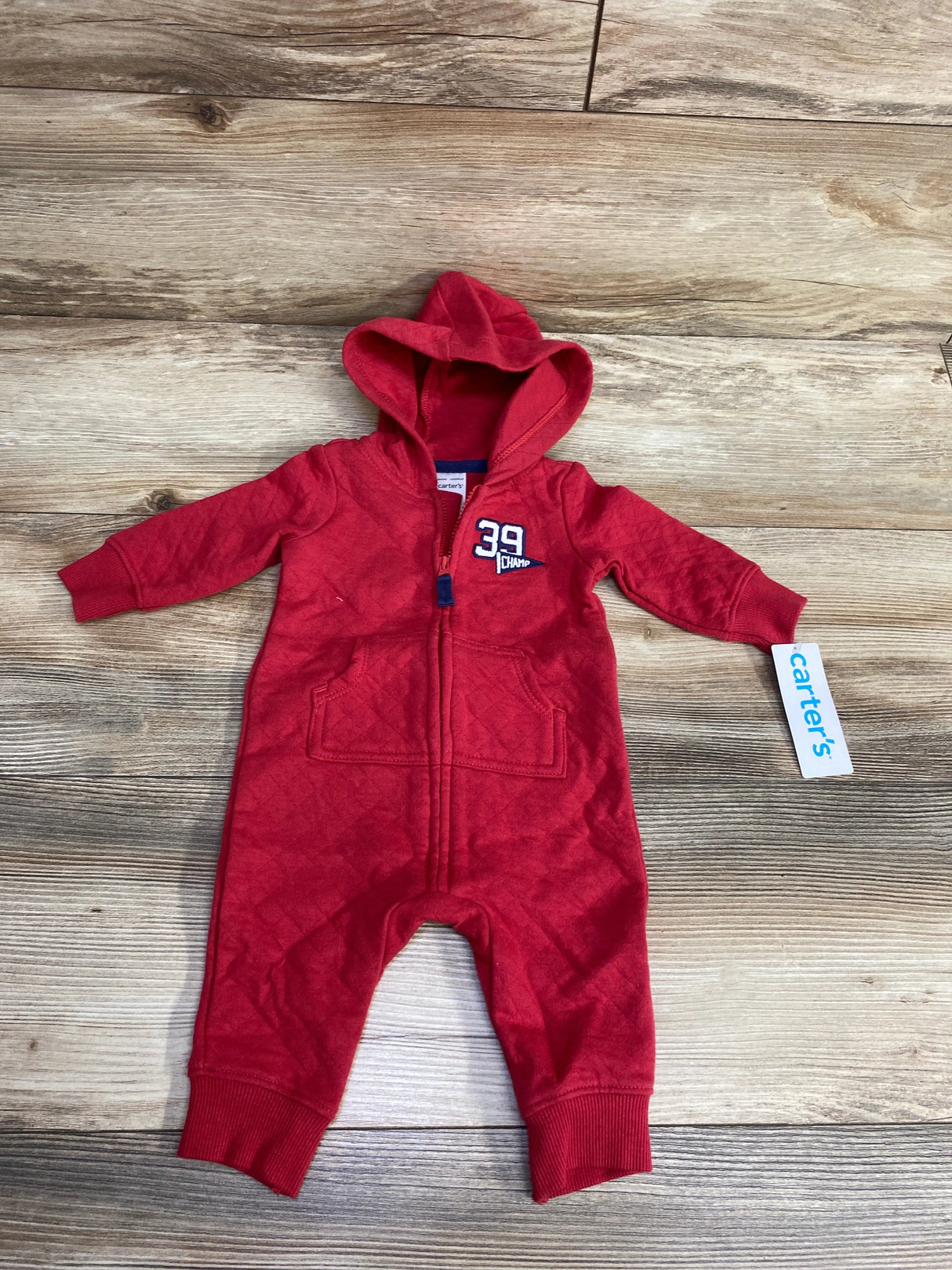 Red baby hooded one-piece romper with zip front and "39 Champ" emblem by Carter's on wood floor