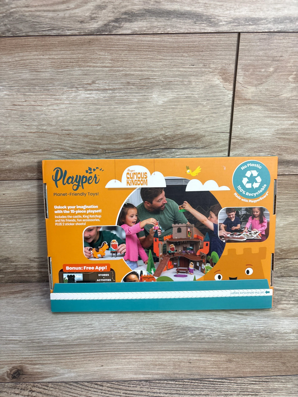 Front view of Playper Curious Kingdom castle box showing castle art, family playing and recyclable badge on orange packaging