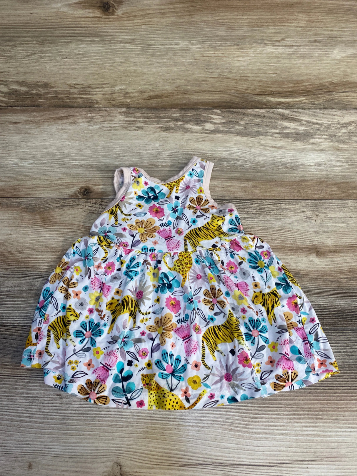 Colorful toddler dress with animal and floral print on wooden background