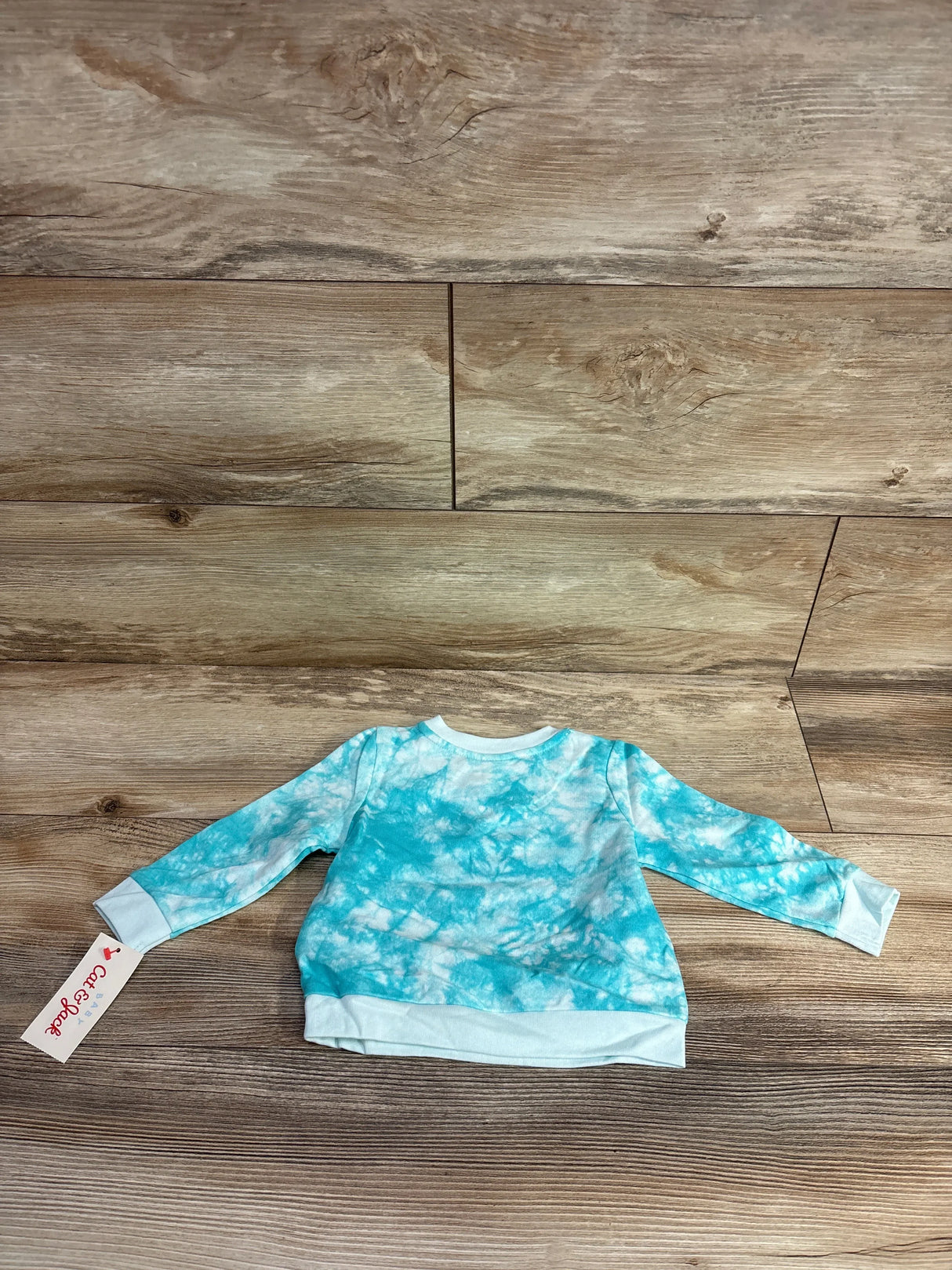Blue and white tie-dye long sleeve baby sweatshirt on wood background