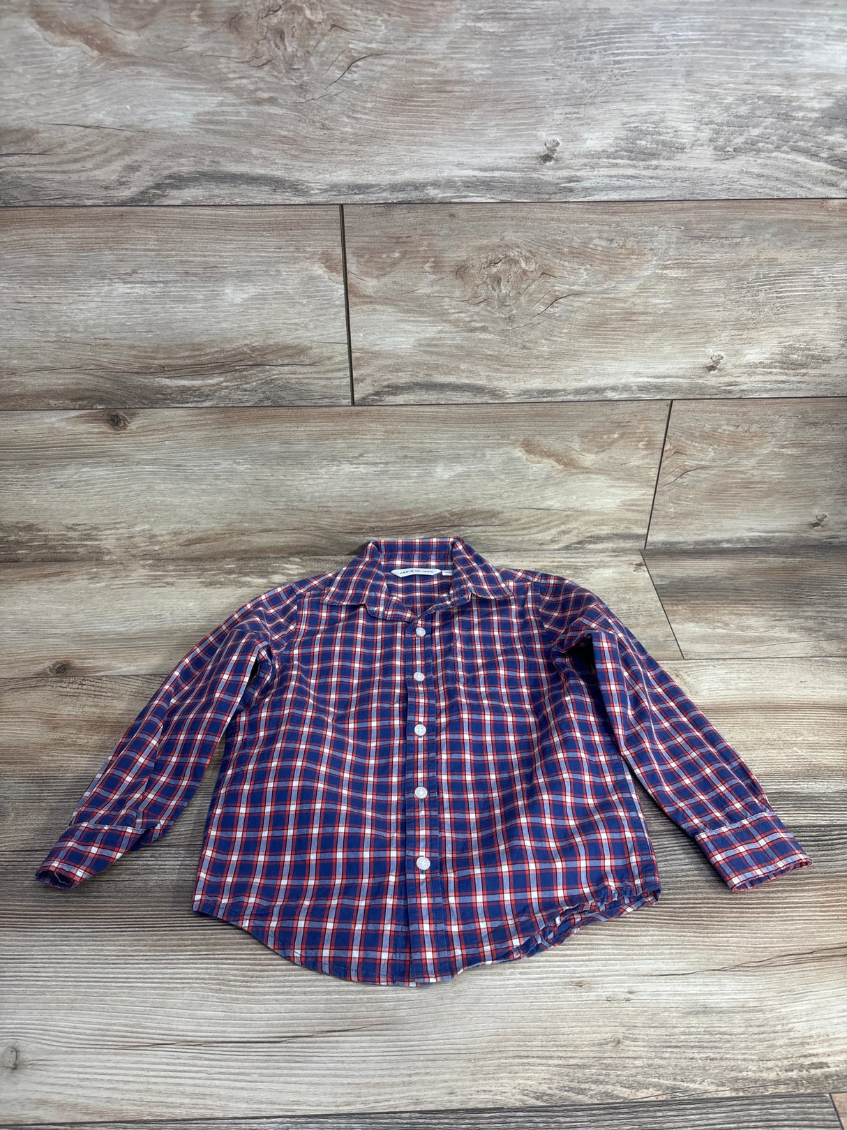 Kids long sleeve blue and red plaid button-up shirt on wood background