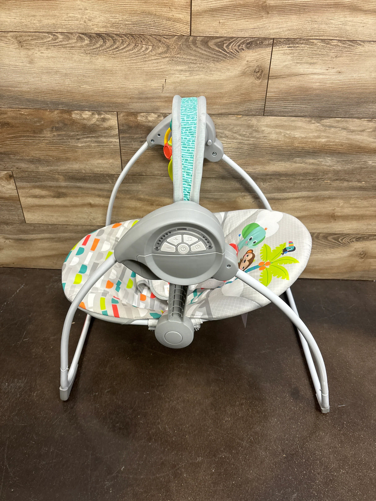 Front view of Bright Starts Playful Paradise swing showing control panel and patterned seat against wood floor