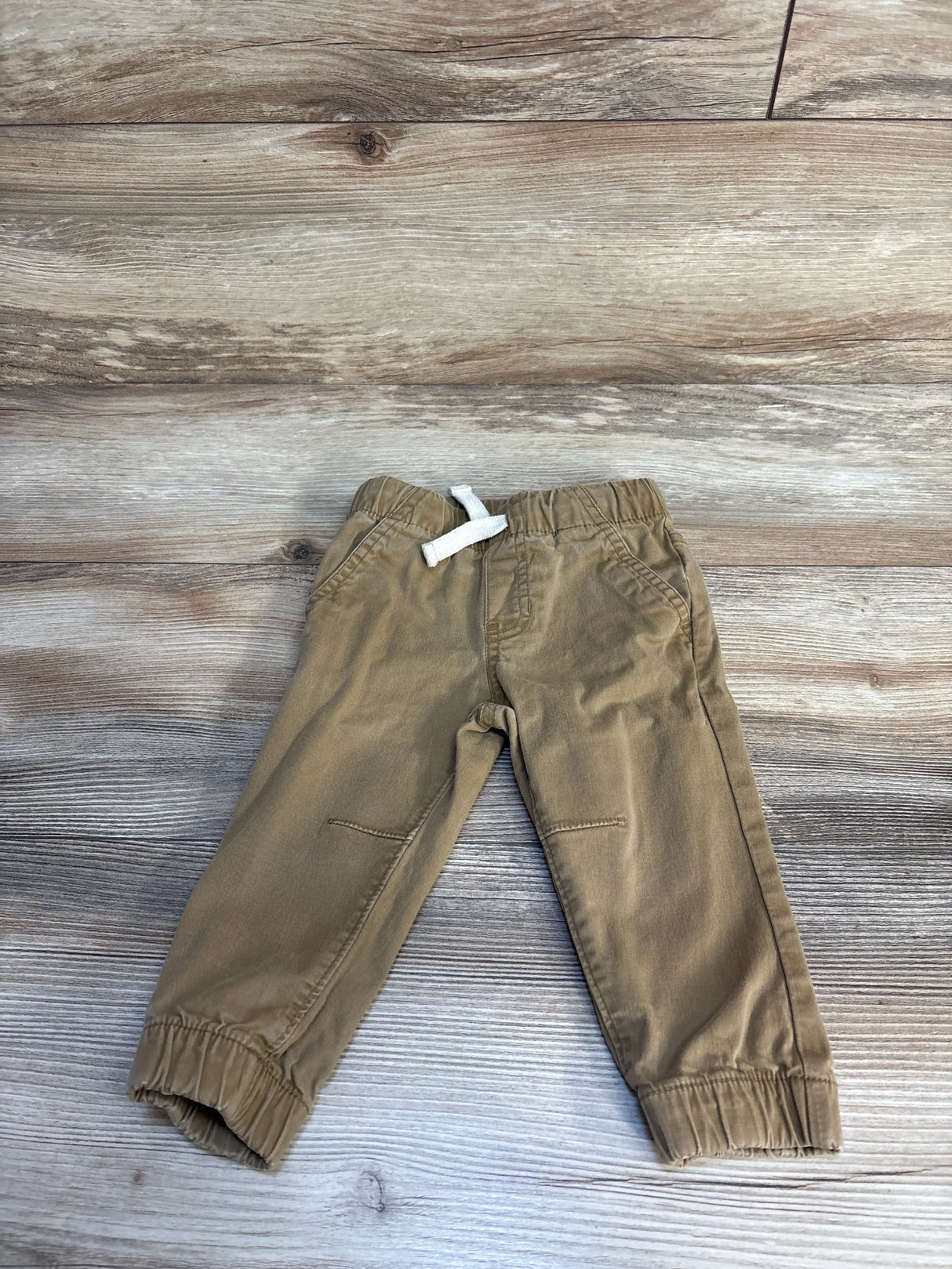 Toddler khaki pants with elastic waistband and drawstring on wood background
