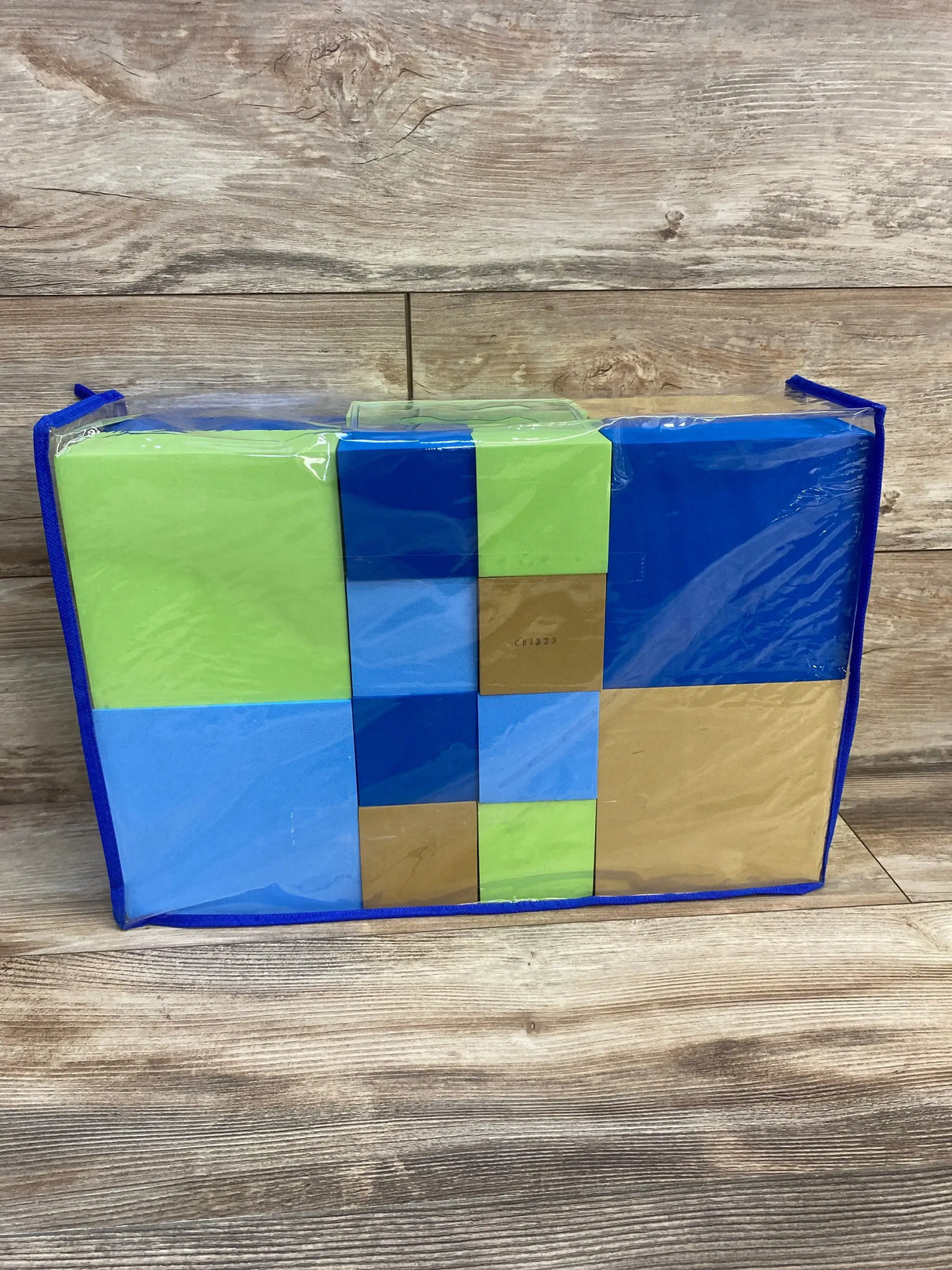 Front view of Lakeshore 26-piece soft blocks in calming blue, green and tan in clear zip bag on wood backdrop
