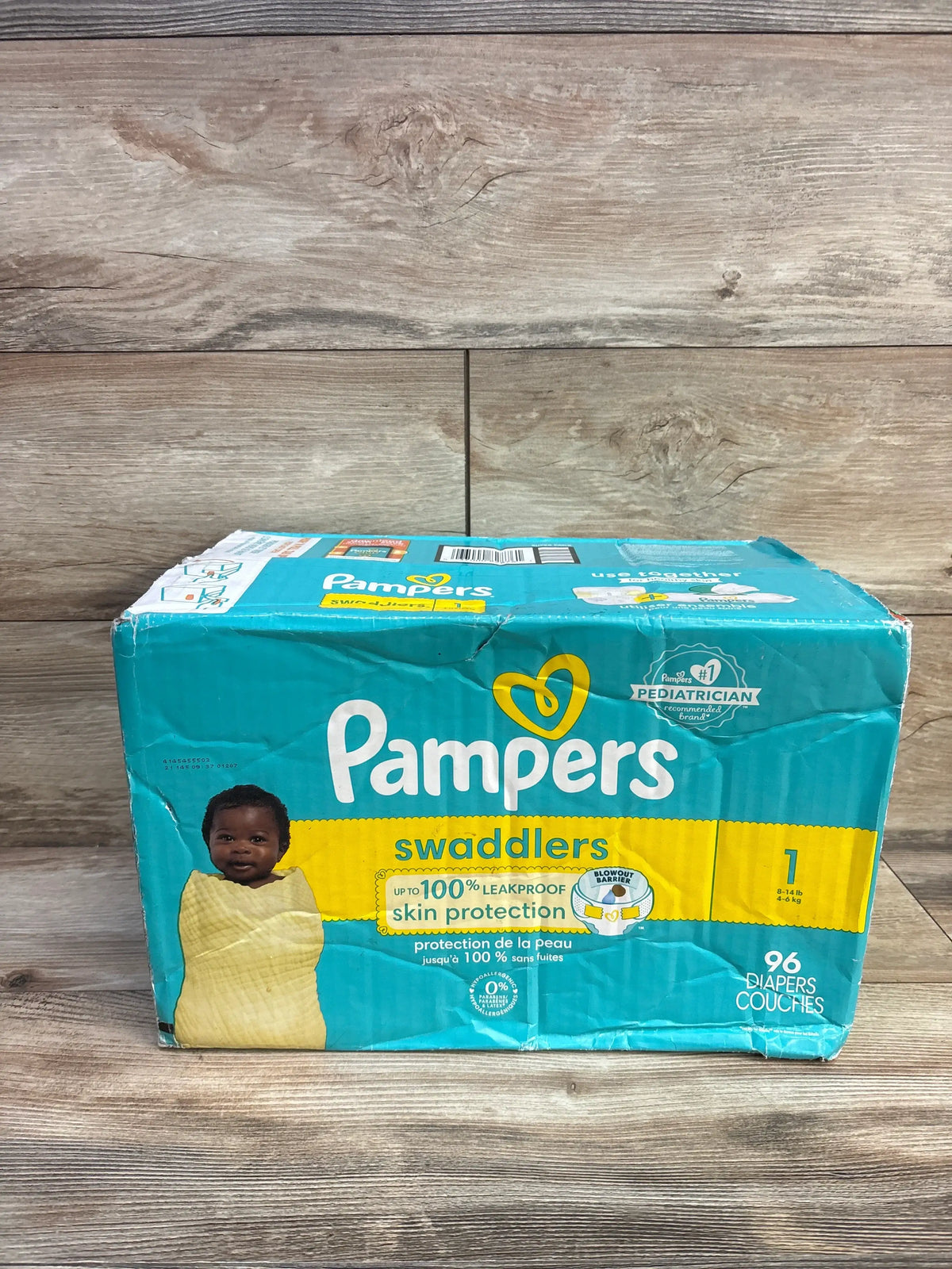 Front view of NEW Pampers Swaddlers Size 1 diaper pack with 96 diapers and leakproof skin protection on wood flooring