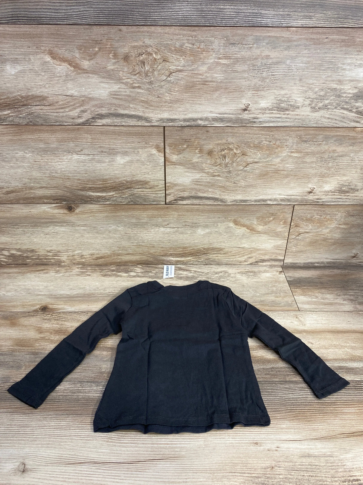 Black long sleeve toddler shirt on wood background, gently used kids clothing resale