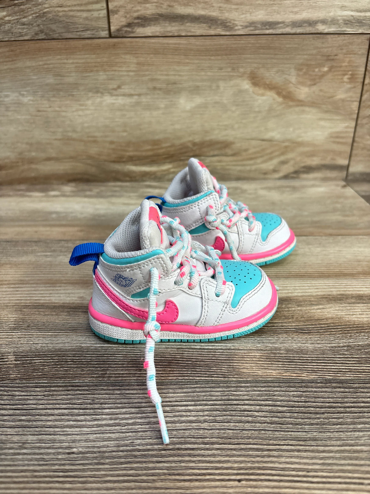 Colorful toddler sneakers with blue and pink accents on wood floor background