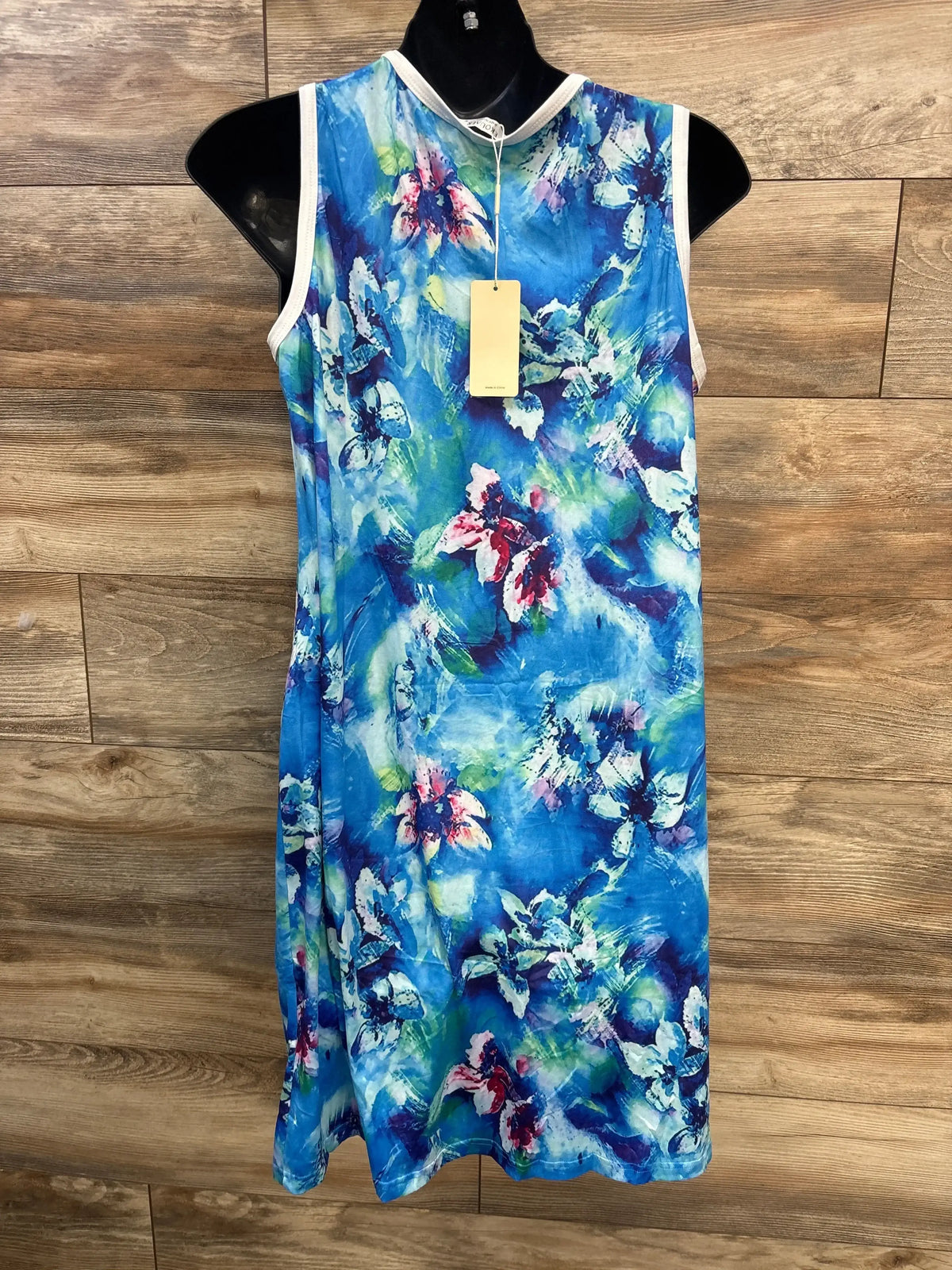 Front view of blue floral tank maternity dress with watercolor print and white trim on mannequin against wood background