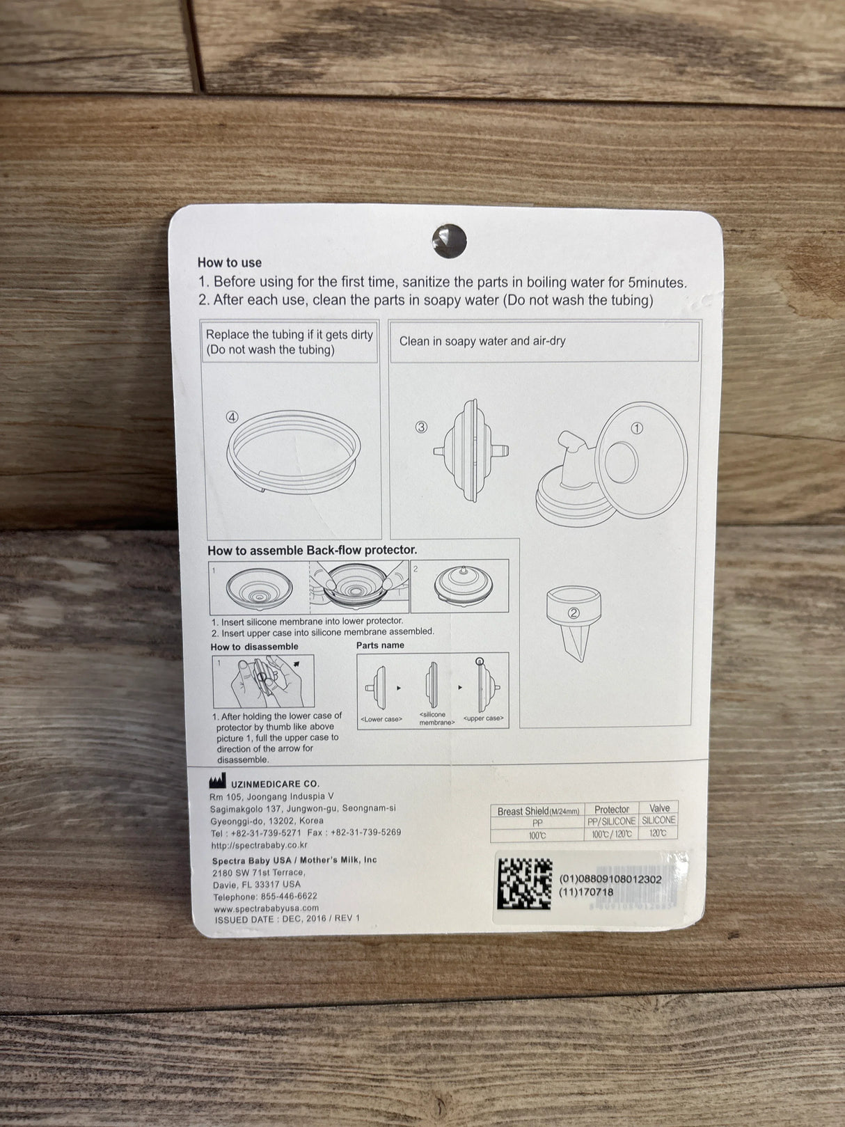 Instruction card for assembling and cleaning Spectra Baby breast pump back-flow protector on wooden surface
