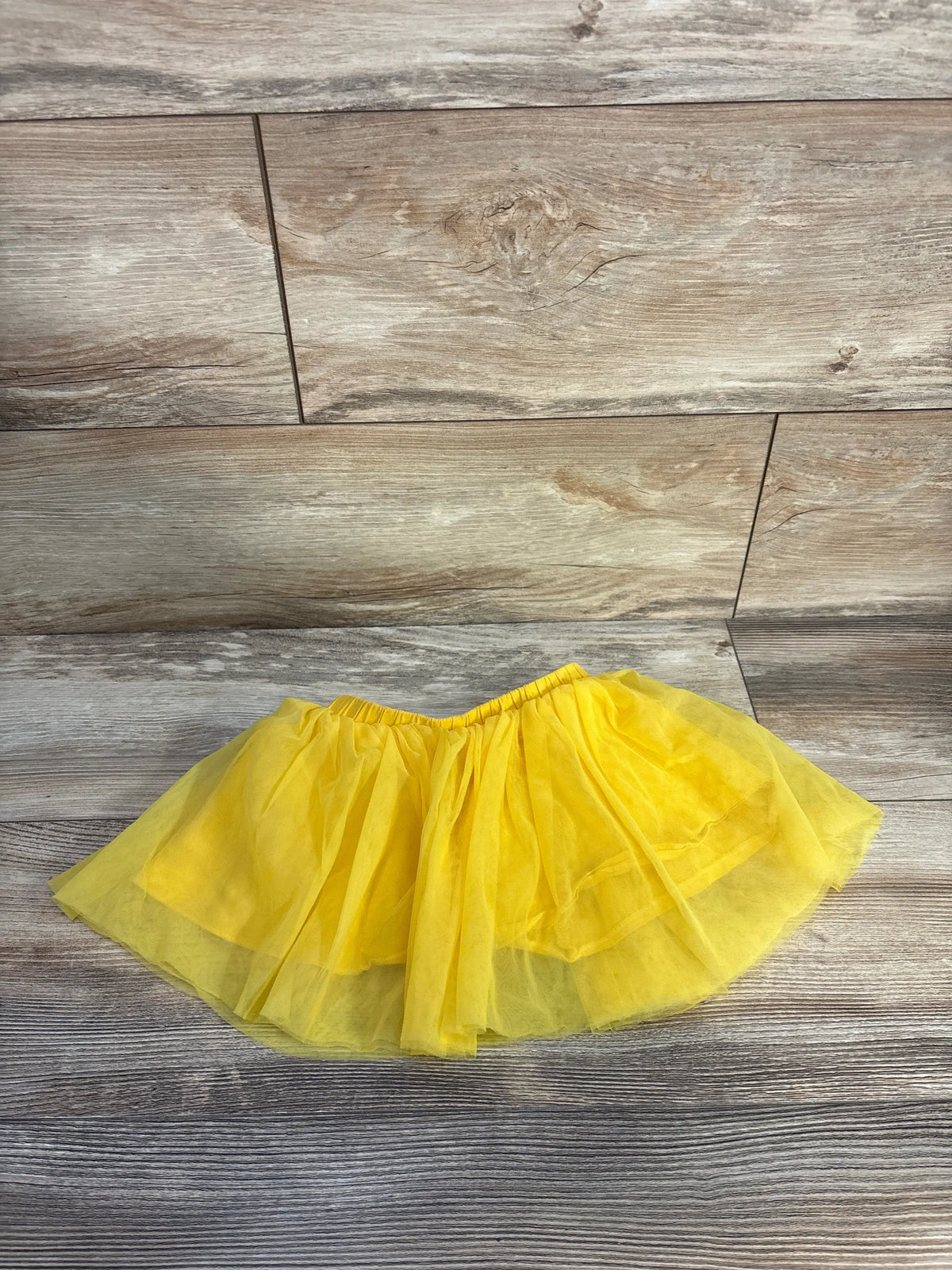 Front view of Shein yellow tulle skirt showcasing layered, twirly silhouette and elastic waistband with wood-look floor background