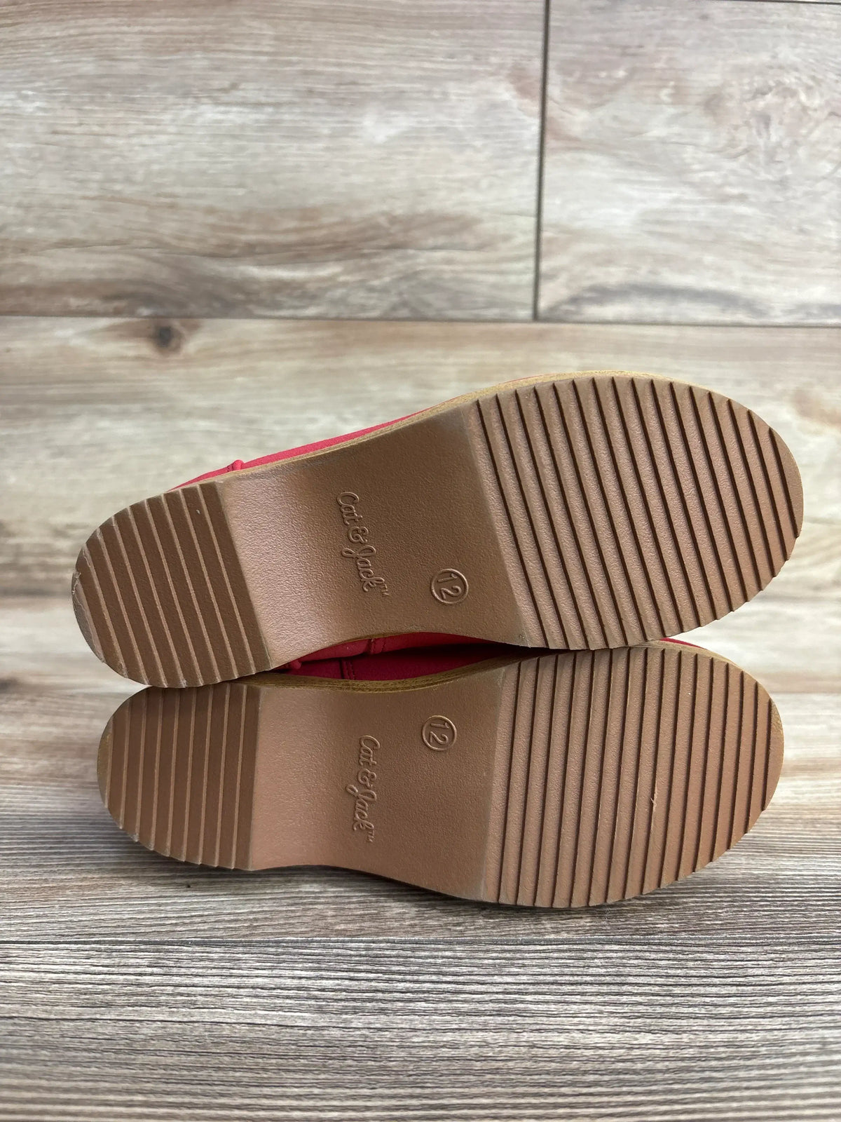 Bottom view of Cat & Jack Etta toddler boots showcasing ribbed non-slip rubber soles and size 12 on wood background