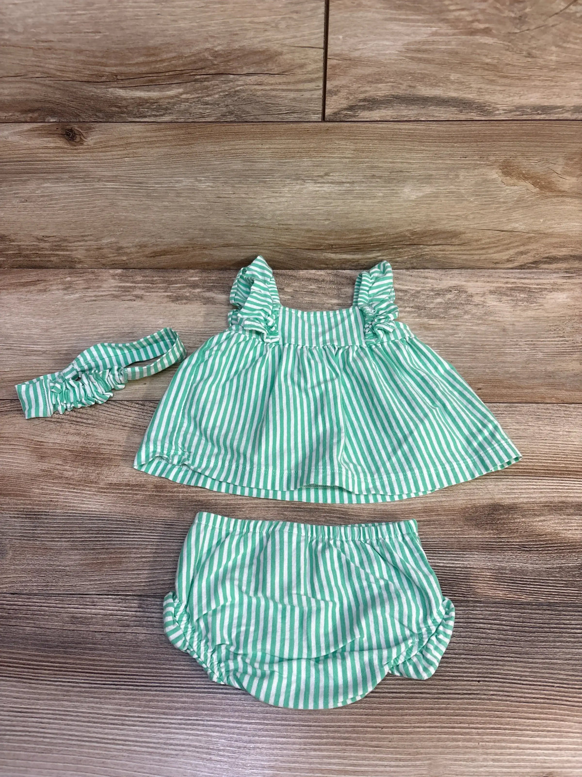Top-down view of Carter’s 3pc striped set showing green and white stripes, smocked peplum top, bloomers, and head bow