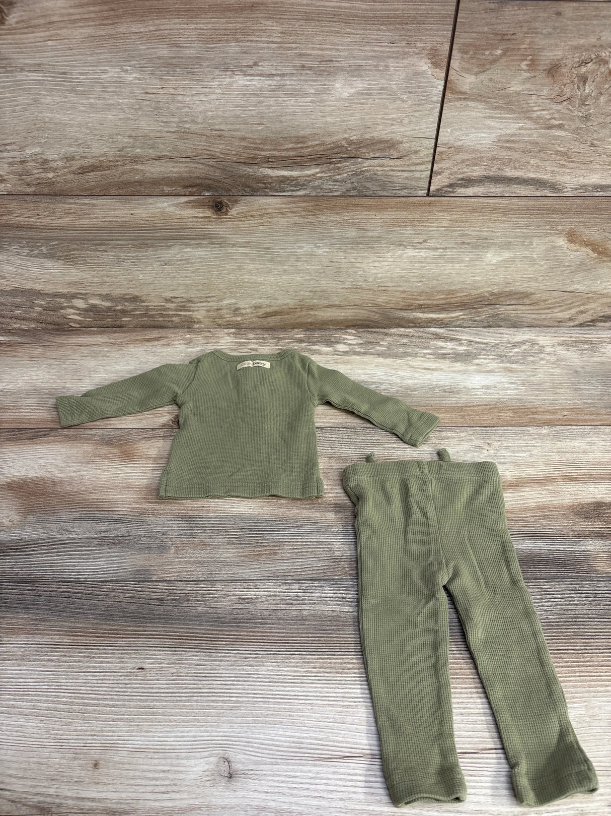 Flat lay of L oved Baby Organic Thermal Henley and Jogger Set sz 0-3m in sage green ribbed knit on wood plank floor