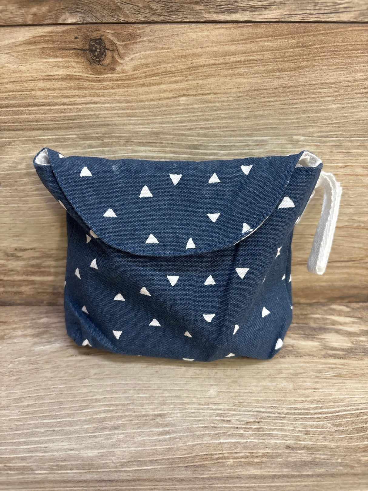 Front view of KiwiCo Panda Crate Shape Puzzle pouch, navy with white triangles, flap and drawstring on wood background
