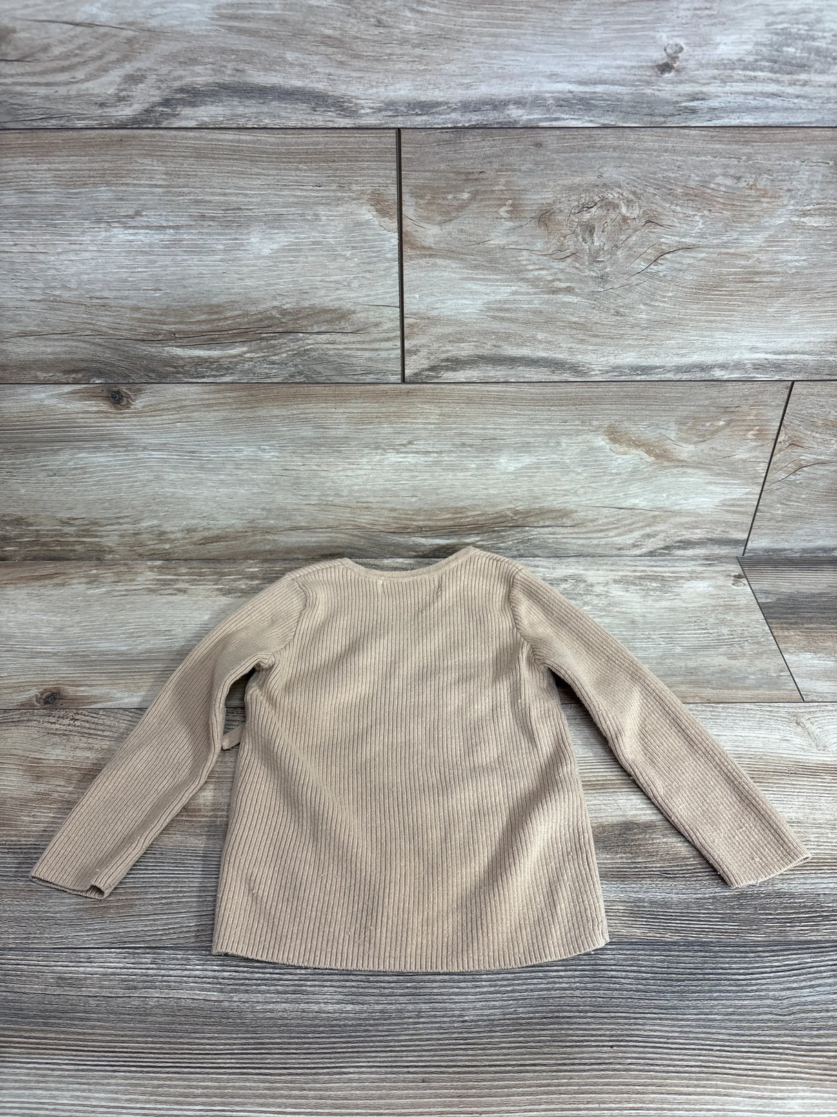 Back view of toddler tan H&M fine knit wrap-front cardigan showcasing ribbed knit texture and long sleeves on wood floor