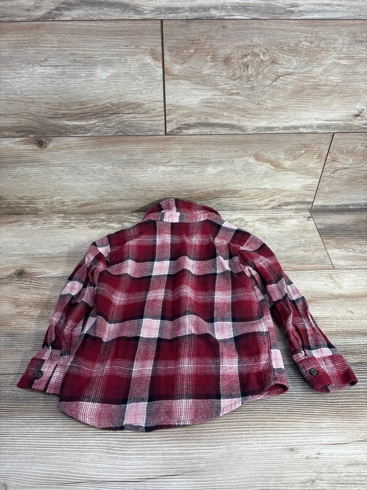 Red and black plaid long sleeve kids flannel shirt on wooden floor