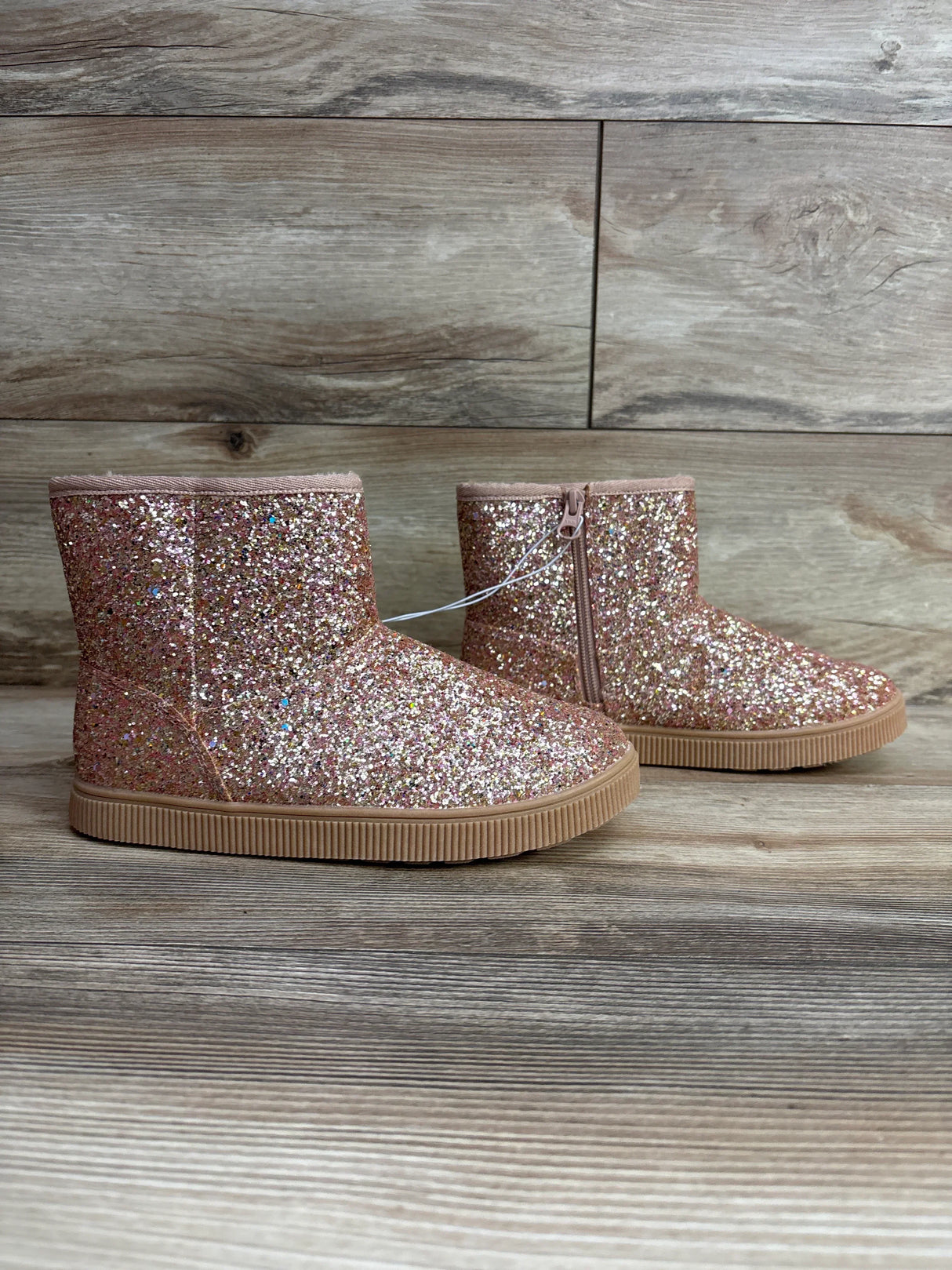 Pink glitter toddler boots with side zipper on wood background, kids footwear