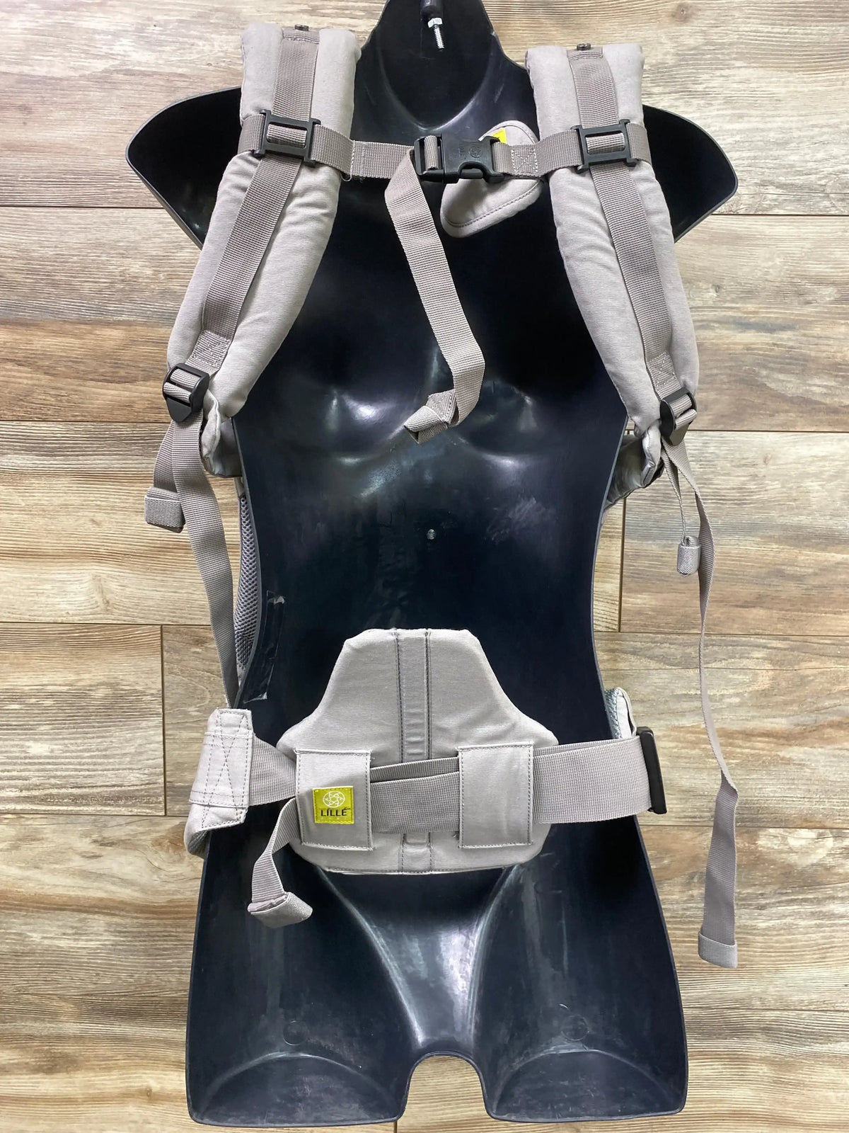 Front view of Lille Baby Complete carrier in stone grey showcasing padded shoulder straps and lumbar waist belt on wood floor