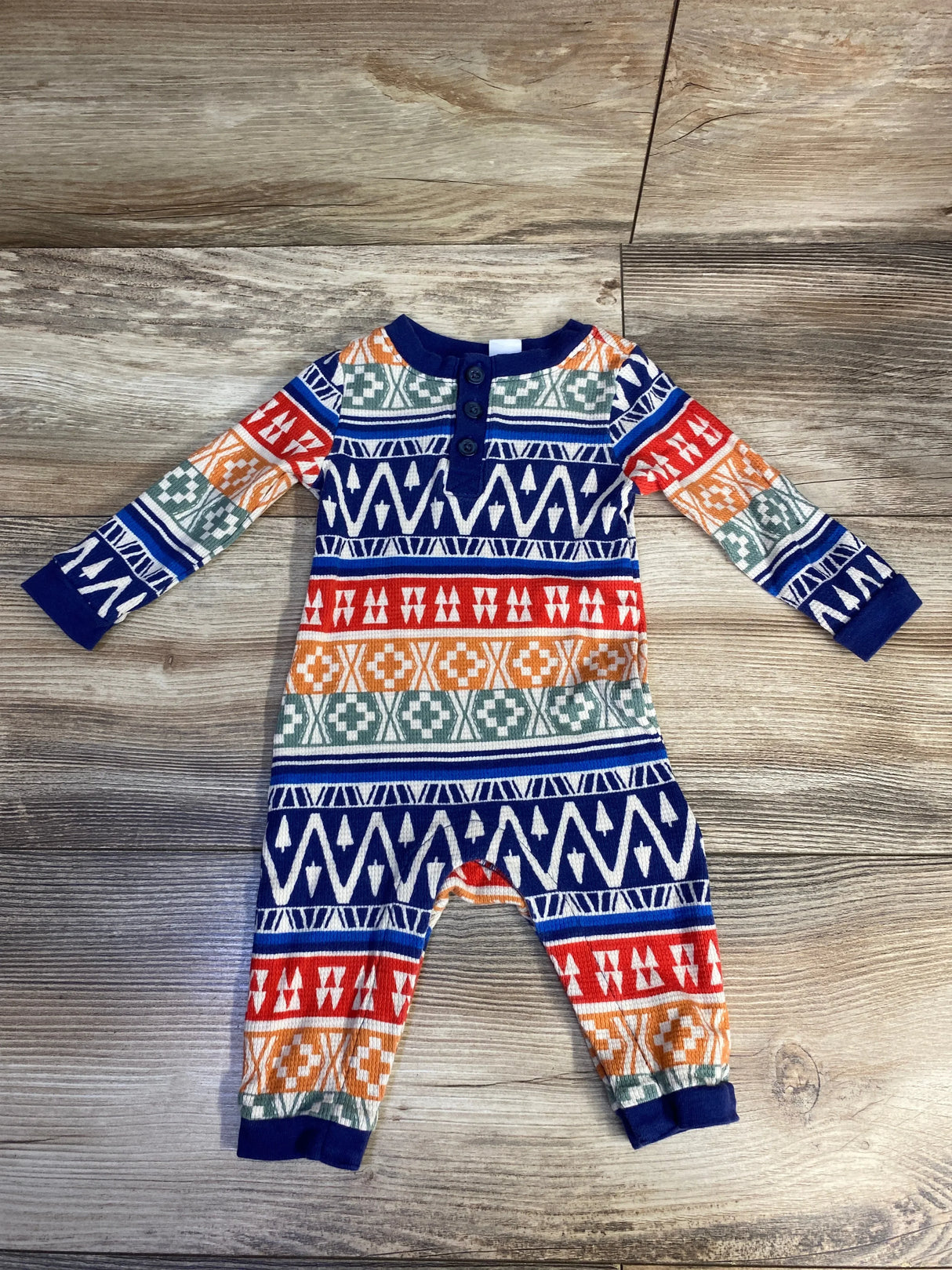 Flat lay of Old Navy thermal coverall 3-6M showing multicolor geometric pattern, henley buttons, navy cuffs