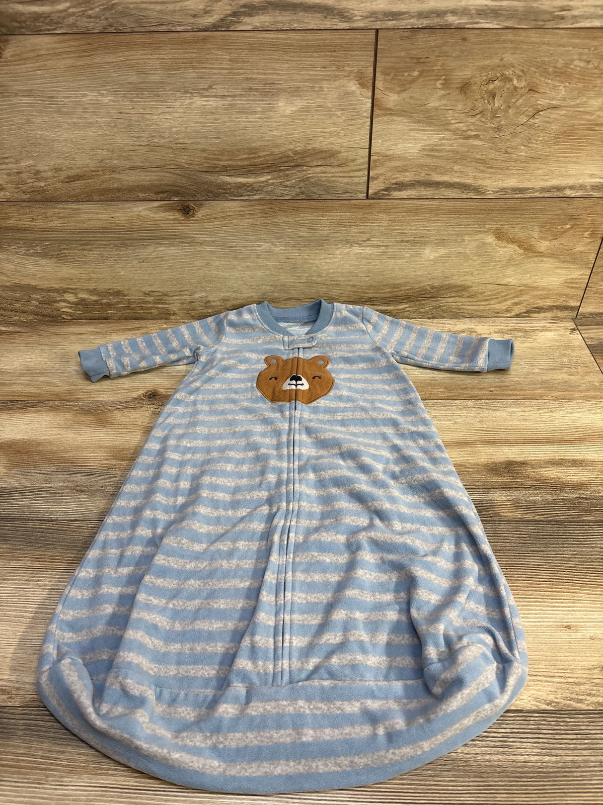 Front view of Carter’s blue striped sleep sack (3-6 months) showing bear chest appliqué and front zipper on wood background
