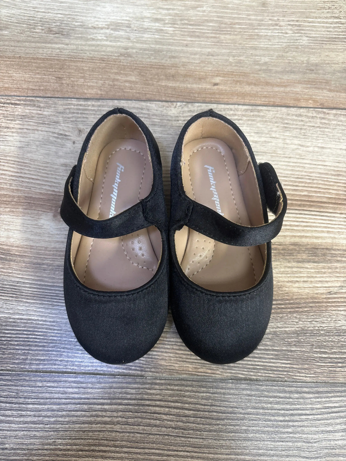 Top view of FunkyMonkey Mary Jane ballet flats in black, size 6C, with Mary Jane straps and round toes on wood grain