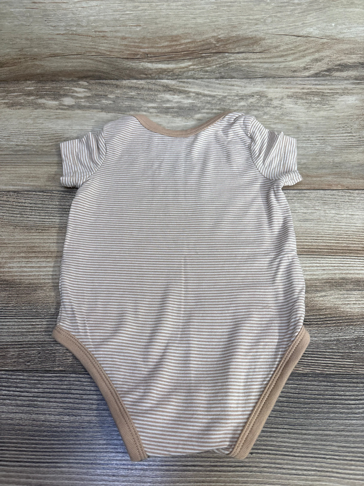 Neutral striped short sleeve baby bodysuit on wood background, gently used kids clothing