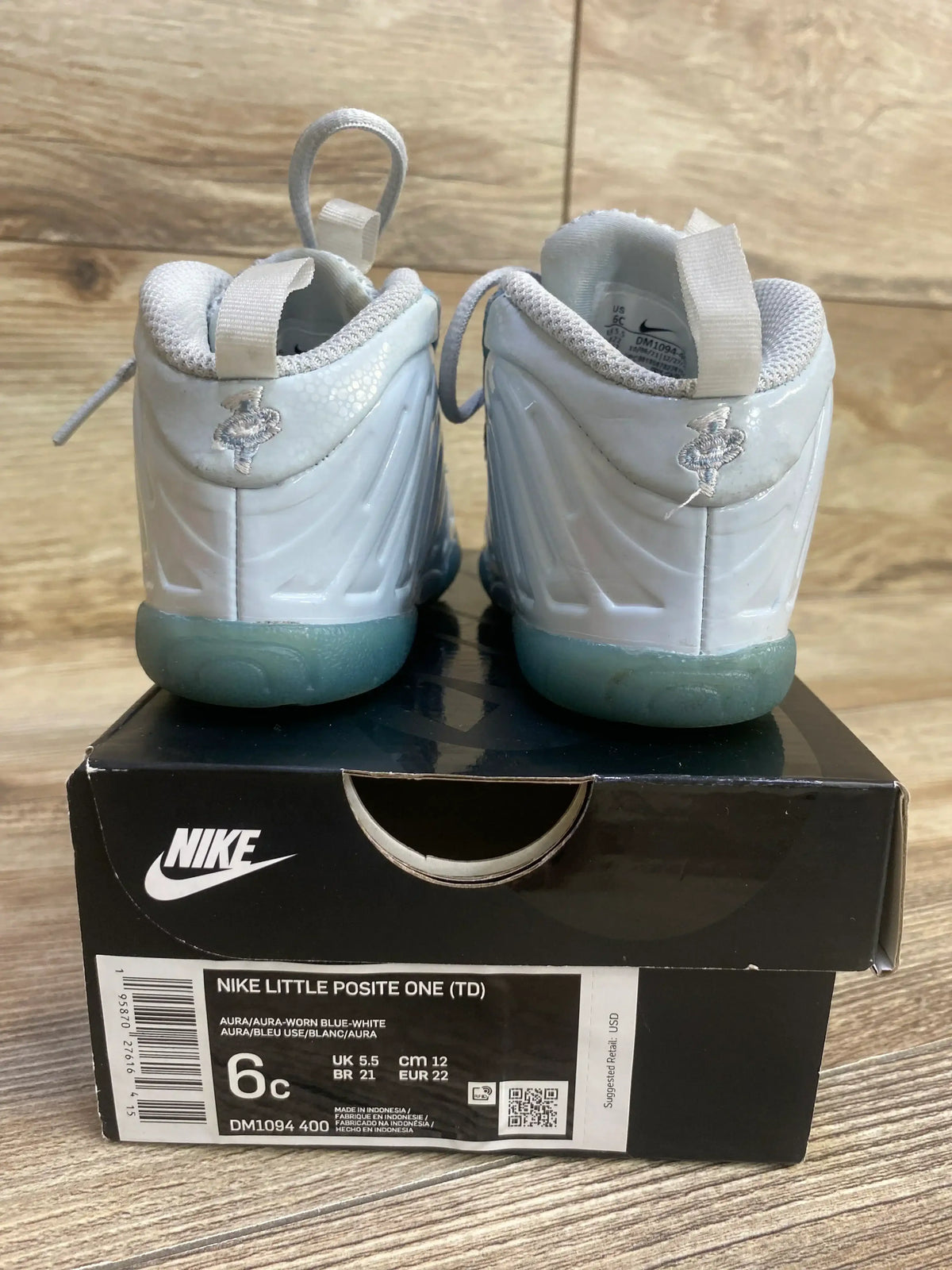 Rear view of Nike Little Posite One TD sneakers in size 6C with glossy molded uppers and translucent blue soles on a shoebox