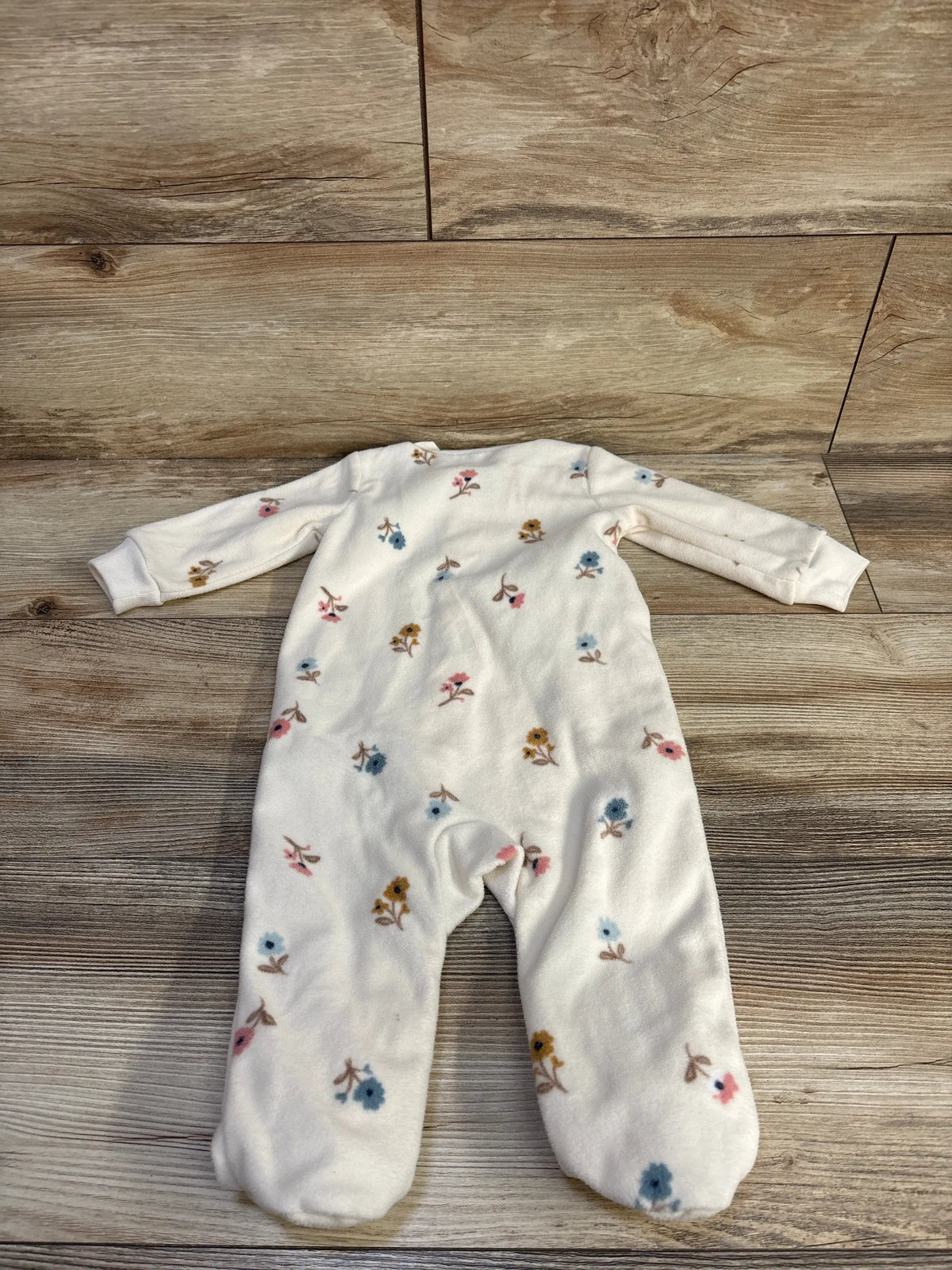 Front view of Carter’s ivory blanket sleeper showcasing long sleeves, footed design, and floral print with wood floor background