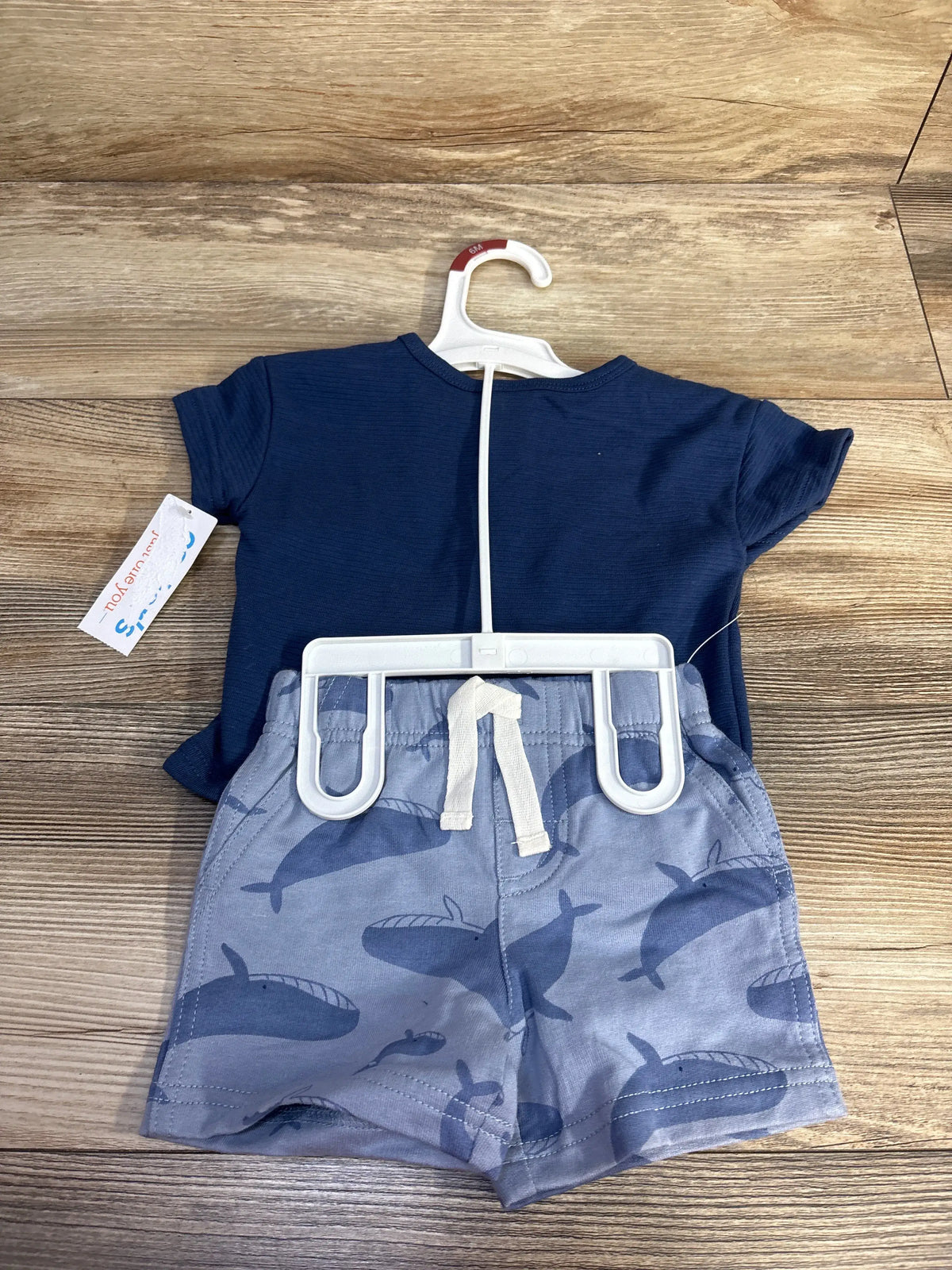 Front view of Just One You two-piece henley shirt and shorts set showcasing navy shirt and whale-print shorts on a wood background