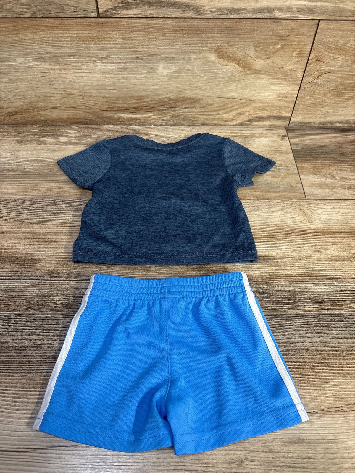 Back view of boys Adidas 2-piece set showing heather navy tee and bright blue shorts with white side stripes on wood floor