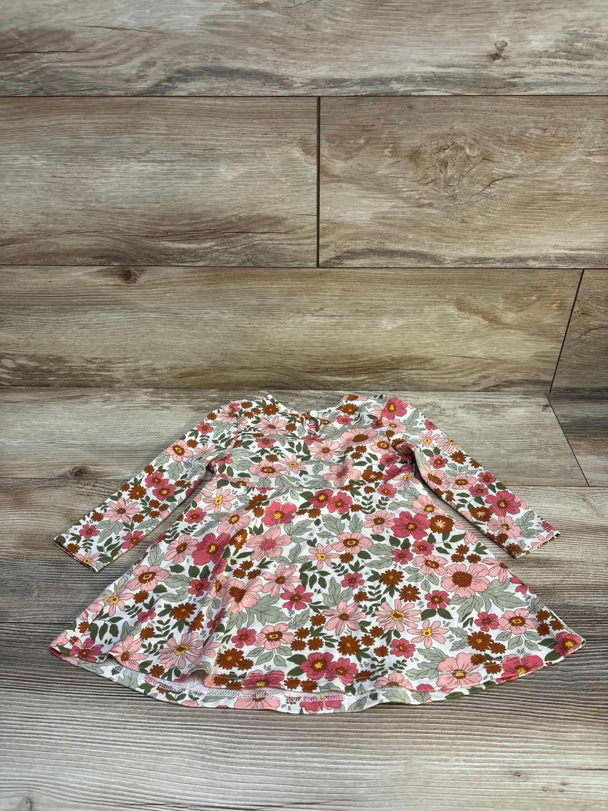 Flat lay of girls long-sleeve floral dress size 18 months with white base and pink and rust flowers, showing twirl skirt and keyhole back on wood floor