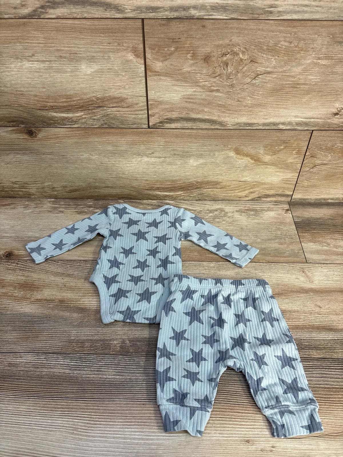 Top view of Cloud Island two-piece ribbed bodysuit and bottoms set showcasing blue star pattern on wood floor